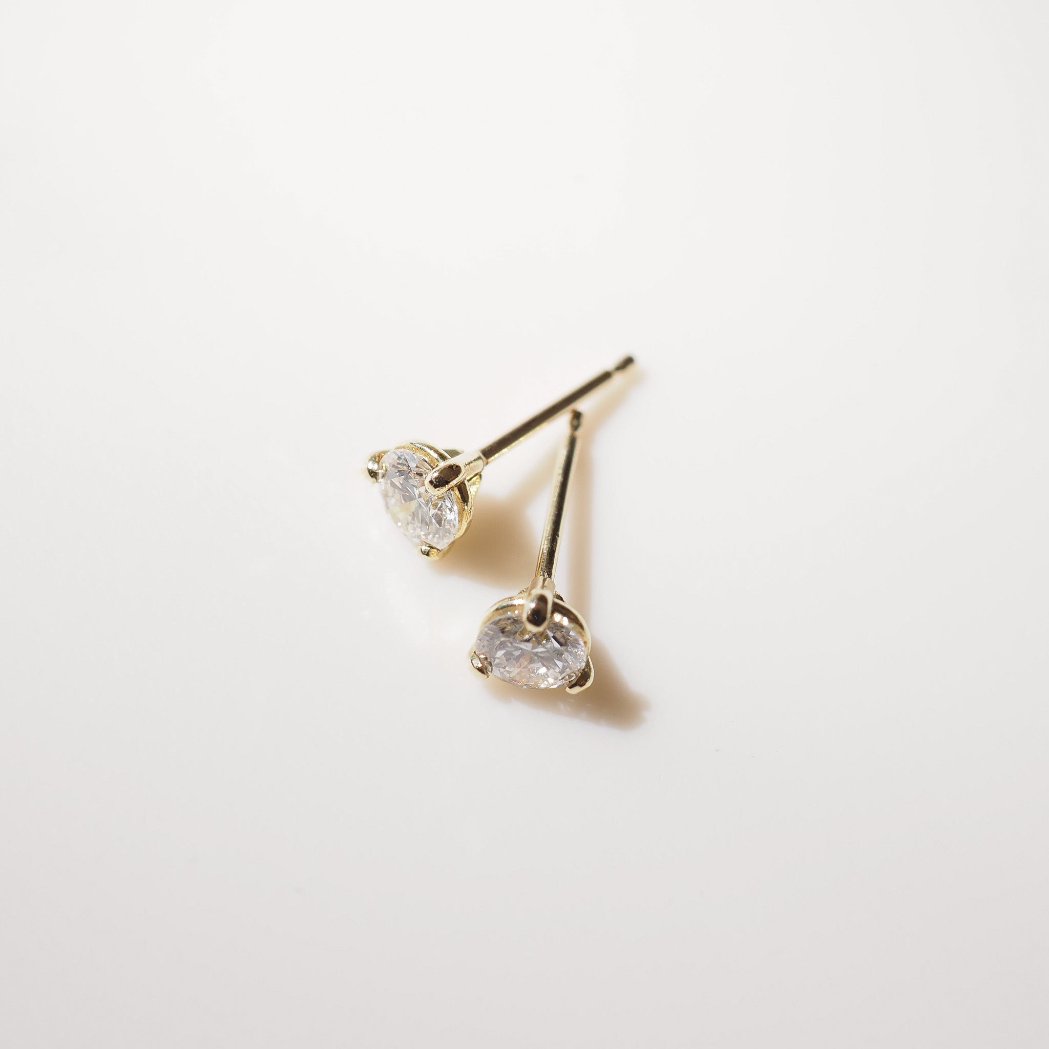 Gold heart-shaped earrings on a light gray background