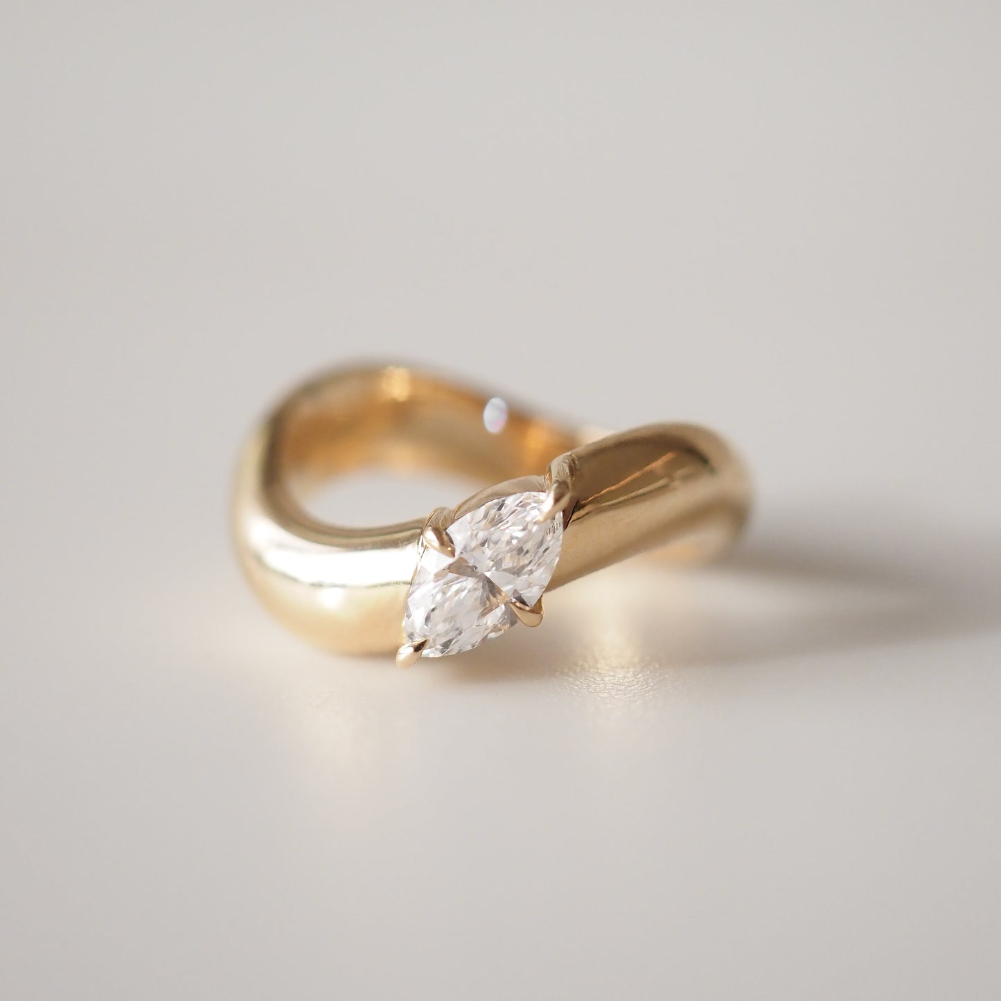 Gold ring with a marquise-cut diamond, featuring a unique twist design, showcased on a light background. Perfect for luxury jewellery seekers.
