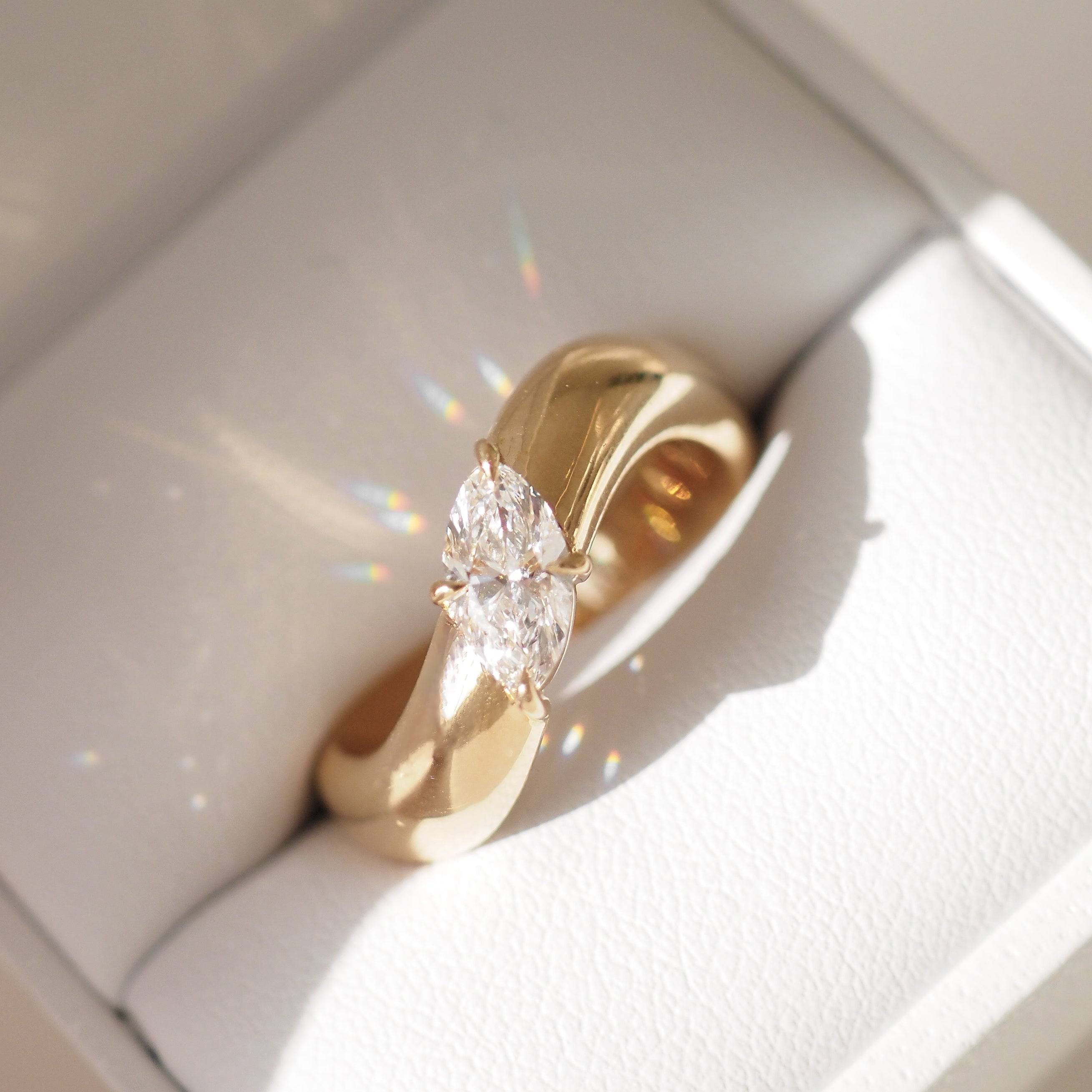 Gold ring with marquise-cut diamond in a luxe jewellery box, reflecting light elegantly. Ideal for high-end jewellery lovers.