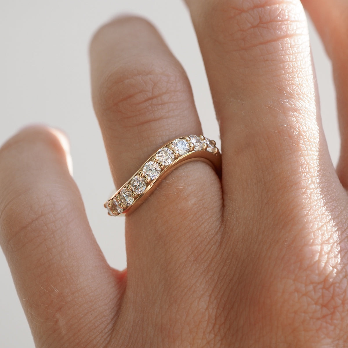 Gold ring adorned with sparkling diamonds on a hand, showcasing luxury jewellery design.