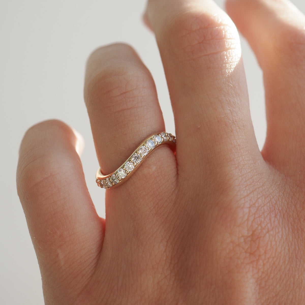 Elegant wavy diamond ring on a woman's finger, showcasing delicate craftsmanship and luxury jewellery design.