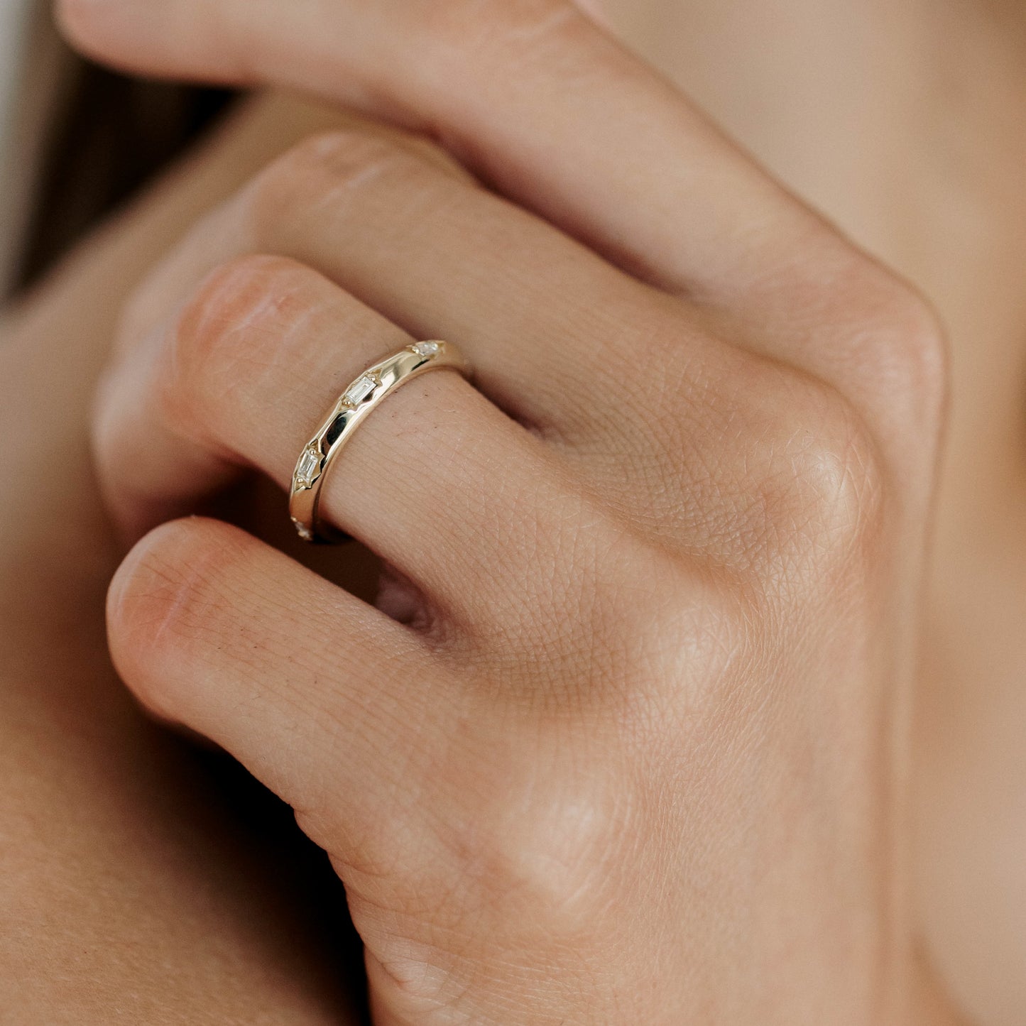 Close-up of a hand wearing an intricately designed gold ring with gemstones, symbolising luxury and elegance in high-end jewellery.