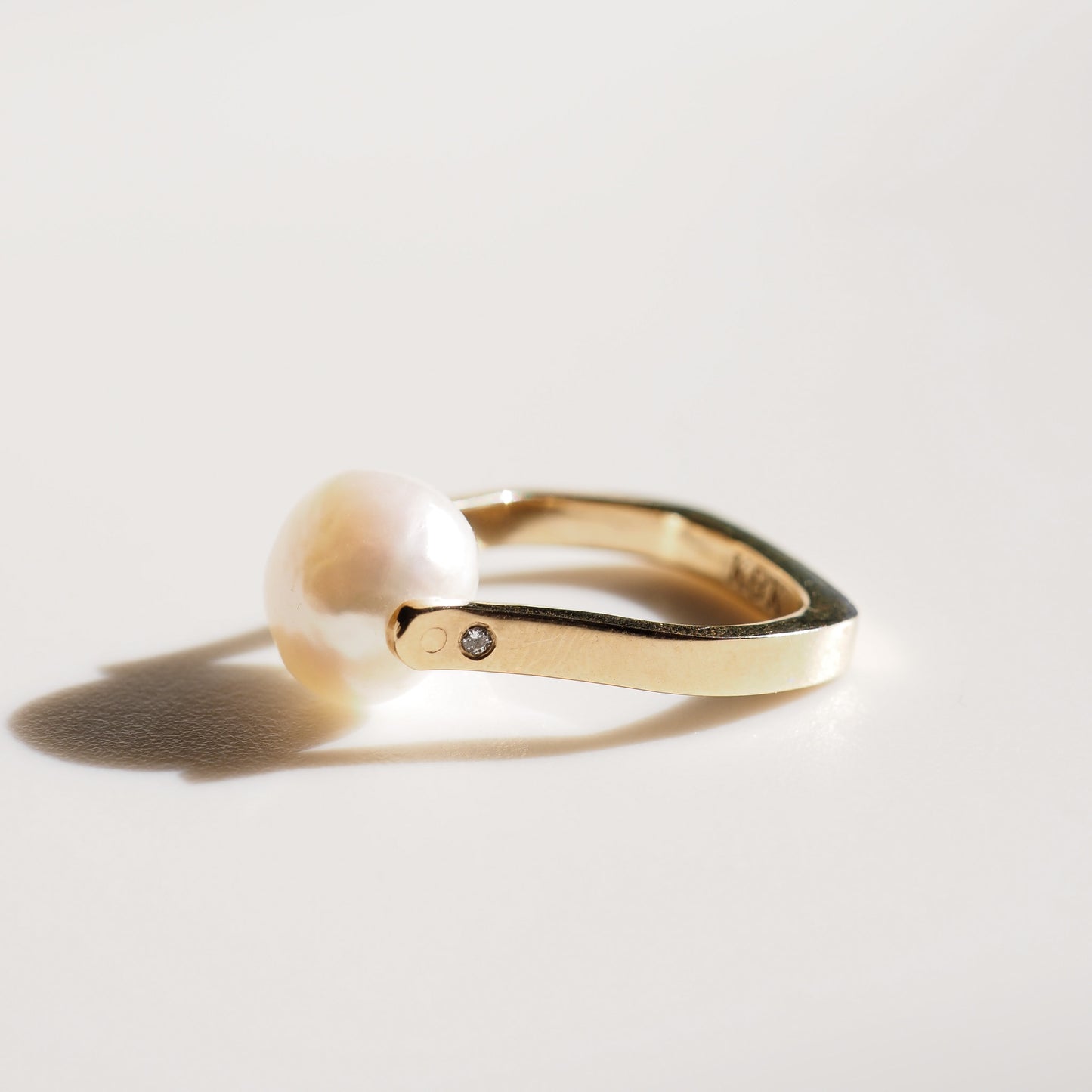 Gold ring with a diamond on a light gray background