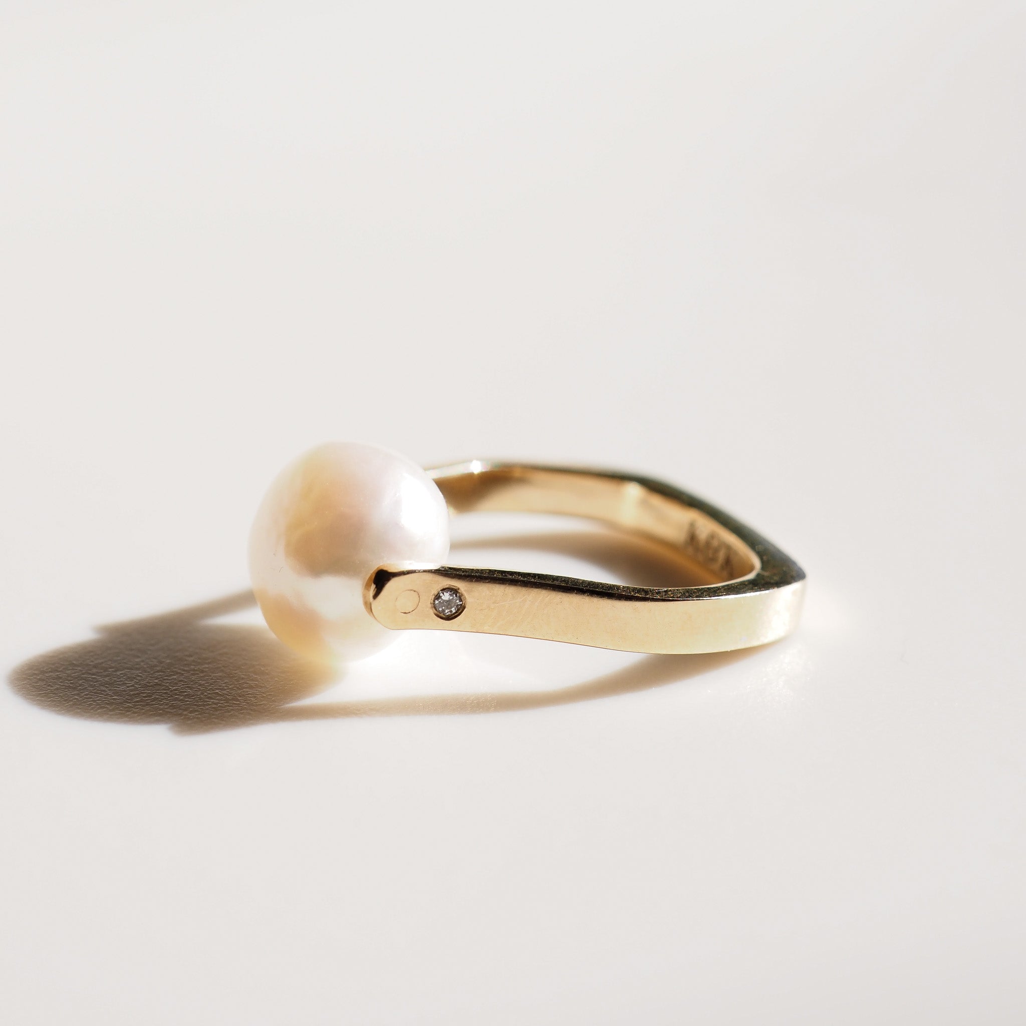 Gold ring with a diamond on a light gray background
