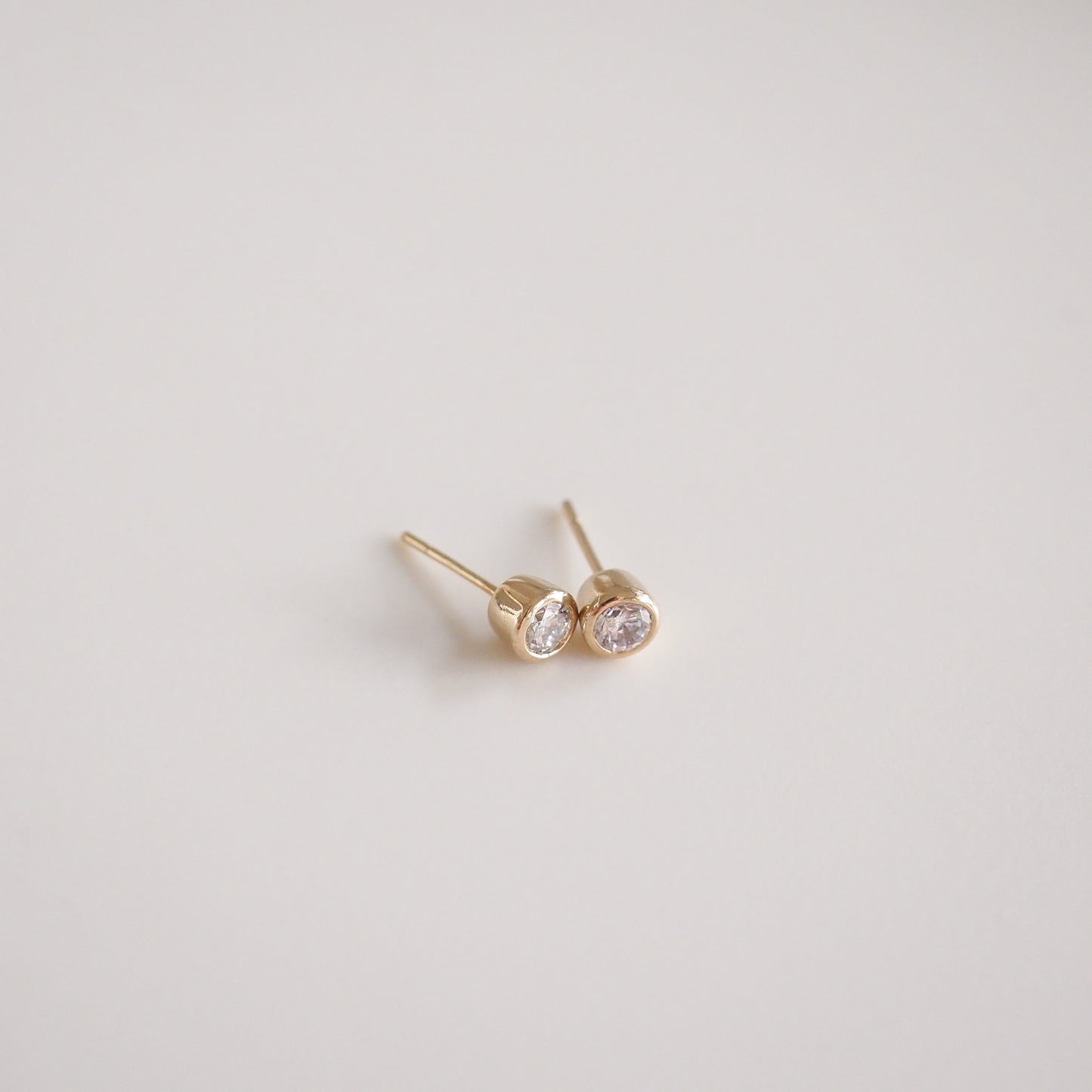 Gold stud earrings with sparkling round diamonds, minimalist luxury jewellery piece on a light background, Australian design.