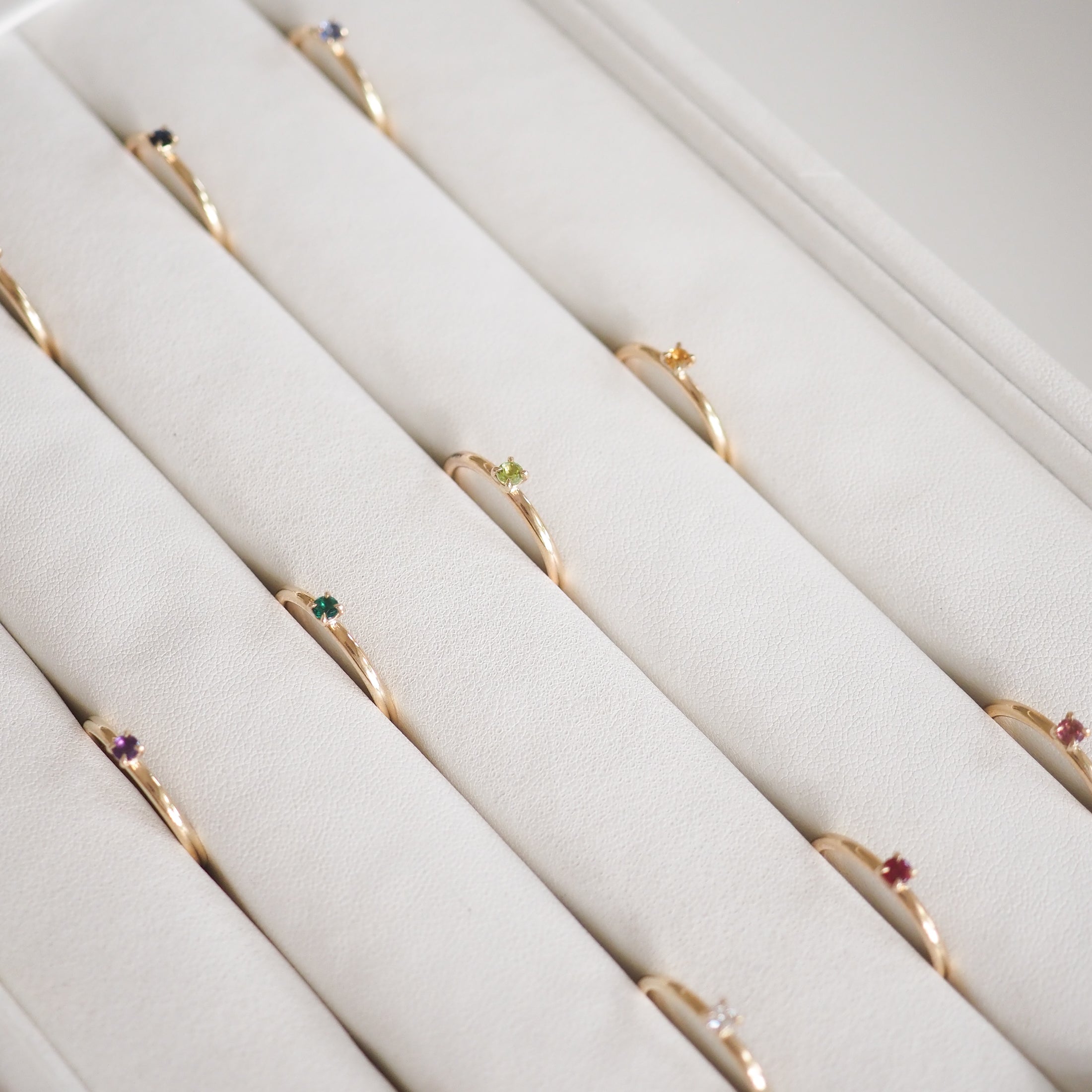 Gold rings with colourful gemstone accents displayed in a white jewellery tray; luxury fashion accessories.