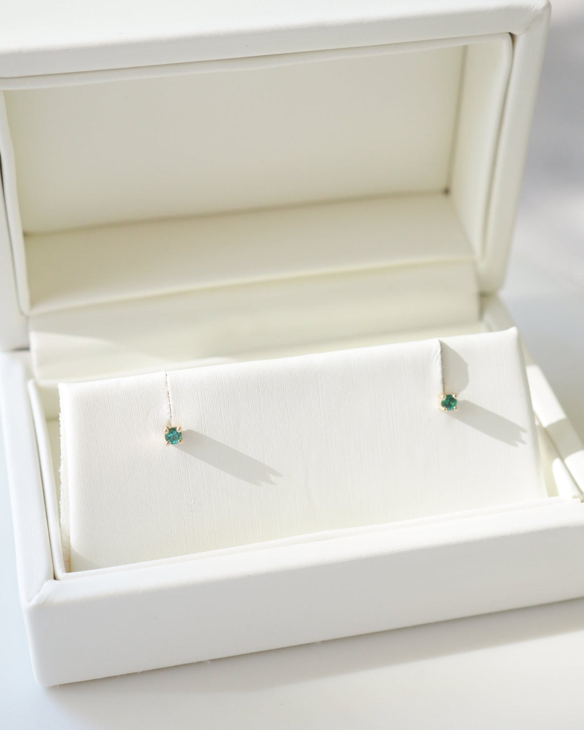 Jewelry box with a pair of earrings inside on a white background