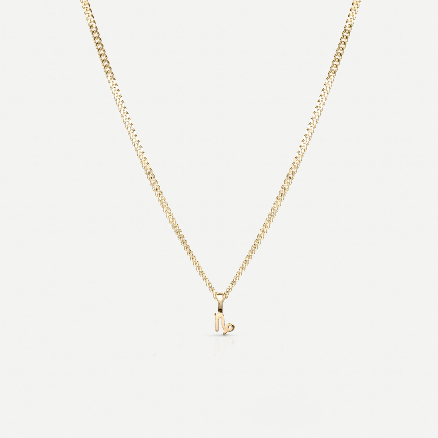 Gold necklace with a delicate Capricorn zodiac pendant on a fine chain, set against a plain white background. Luxurious jewellery piece.