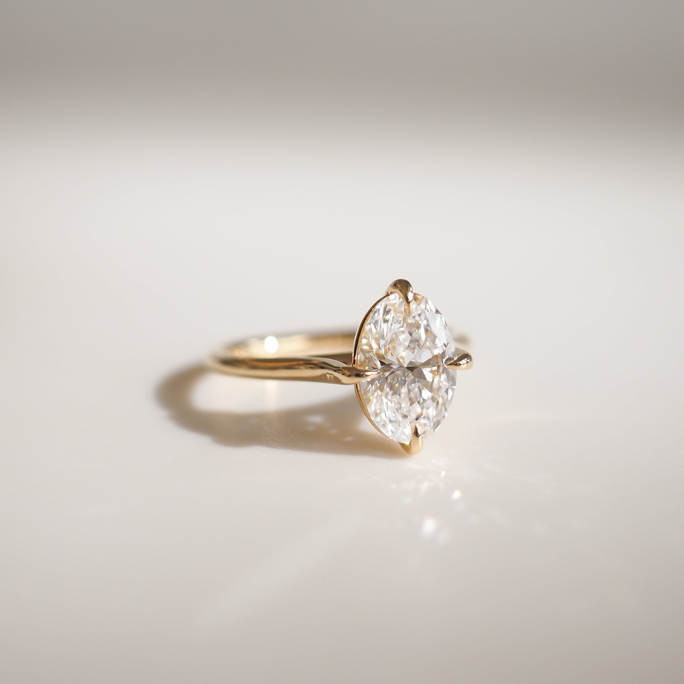 A close-up of a gold ring featuring a marquise-cut diamond set in a simple prong setting, elegantly displayed on a light background.