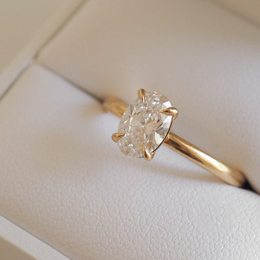 Gold engagement ring with a large oval diamond, elegantly displayed in a white jewellery box. Perfect luxury accessory for special occasions.