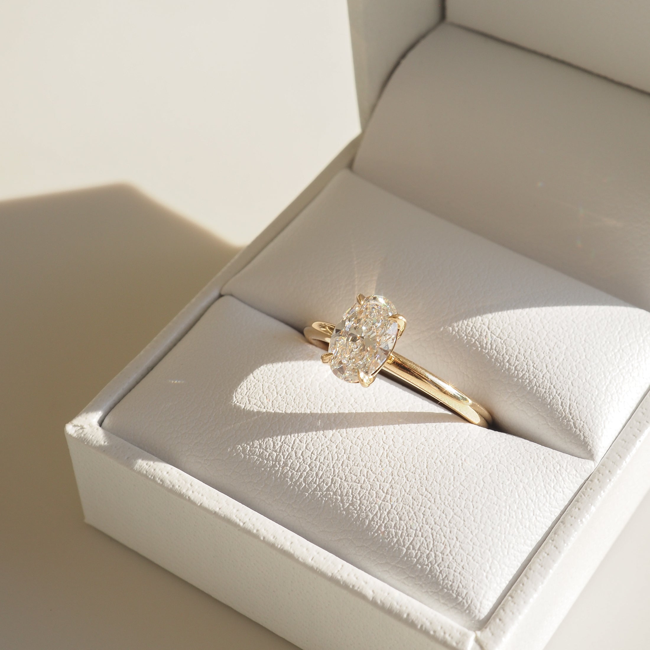 Elegant gold ring with sparkling diamond in a white jewellery box. Refined, luxurious, perfect for engagements.