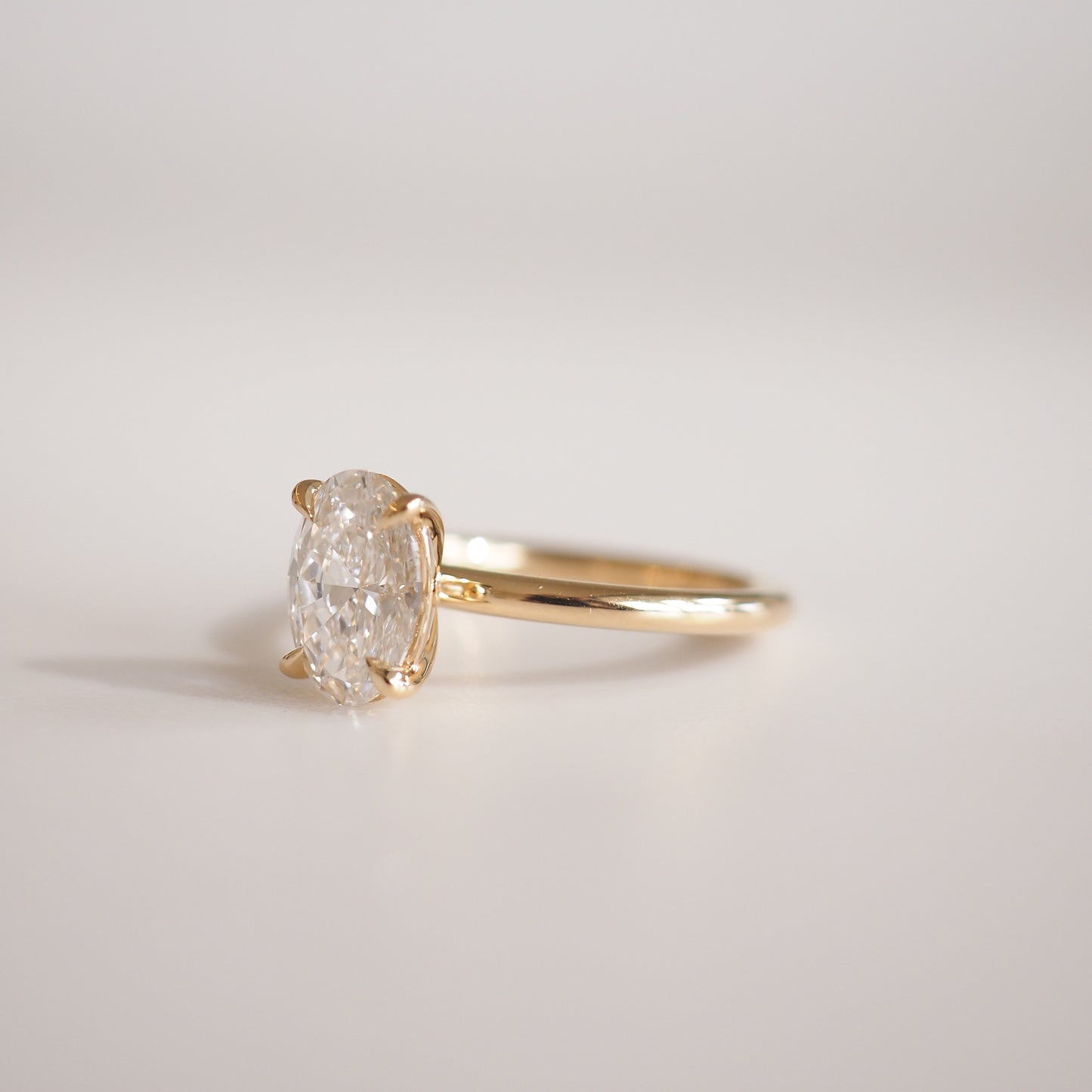 Elegant gold solitaire ring with an oval diamond setting on a smooth band, showcasing luxury jewellery.