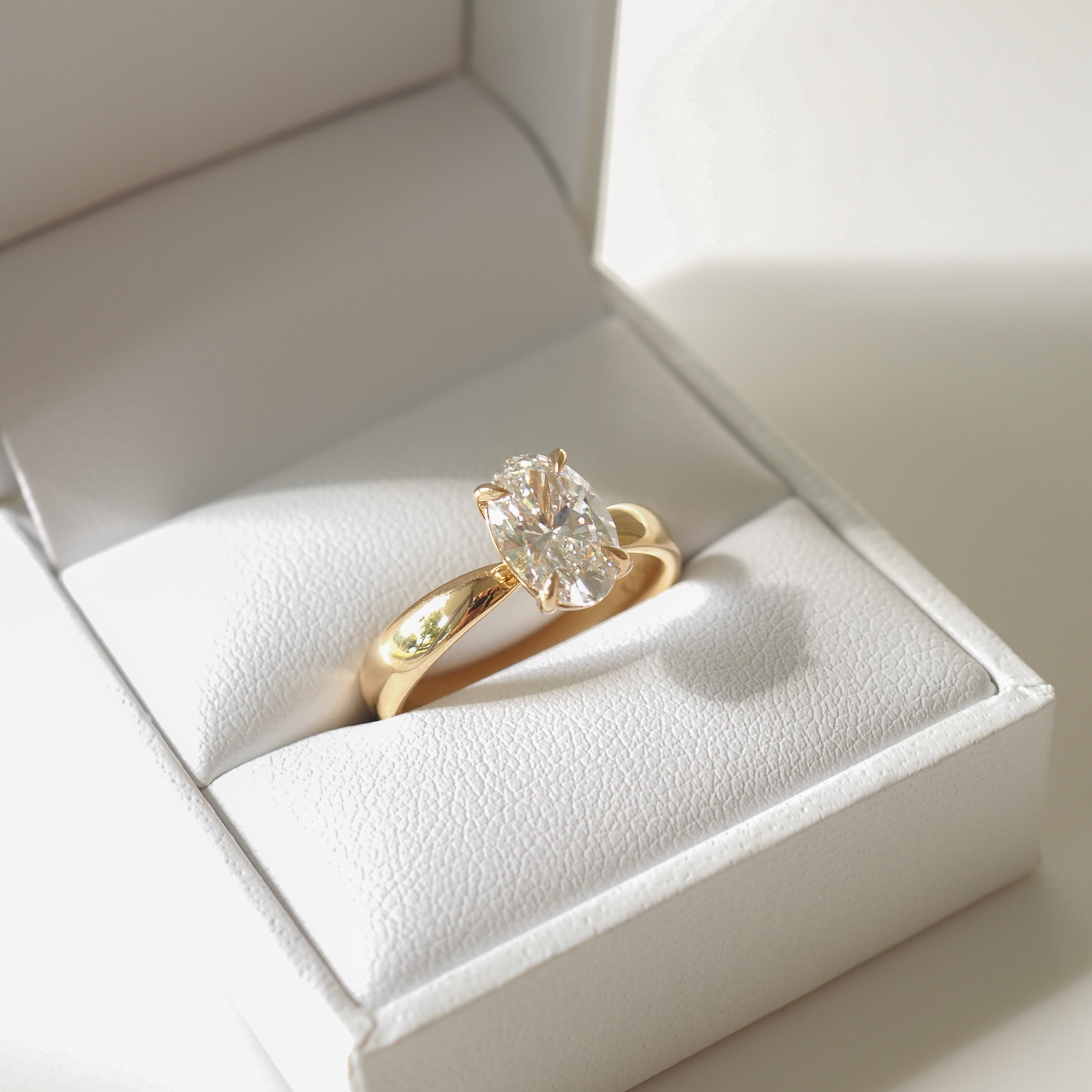Gold ring with large oval diamond in white jewellery box. Luxurious, high-end detail. Perfect for Australian fine jewellery lovers.