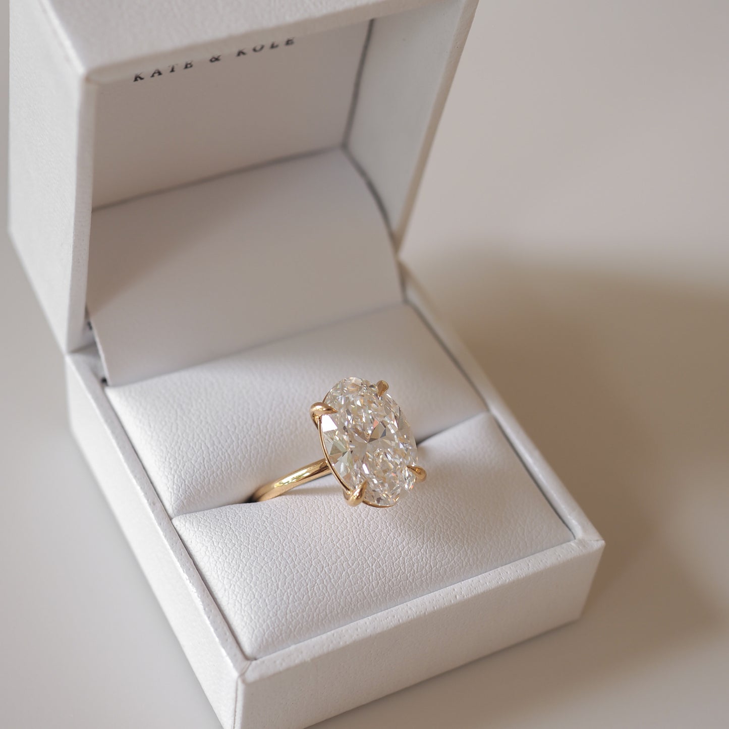 Gold ring with a large oval diamond in a white jewellery box. Perfect for luxurious engagements or weddings.