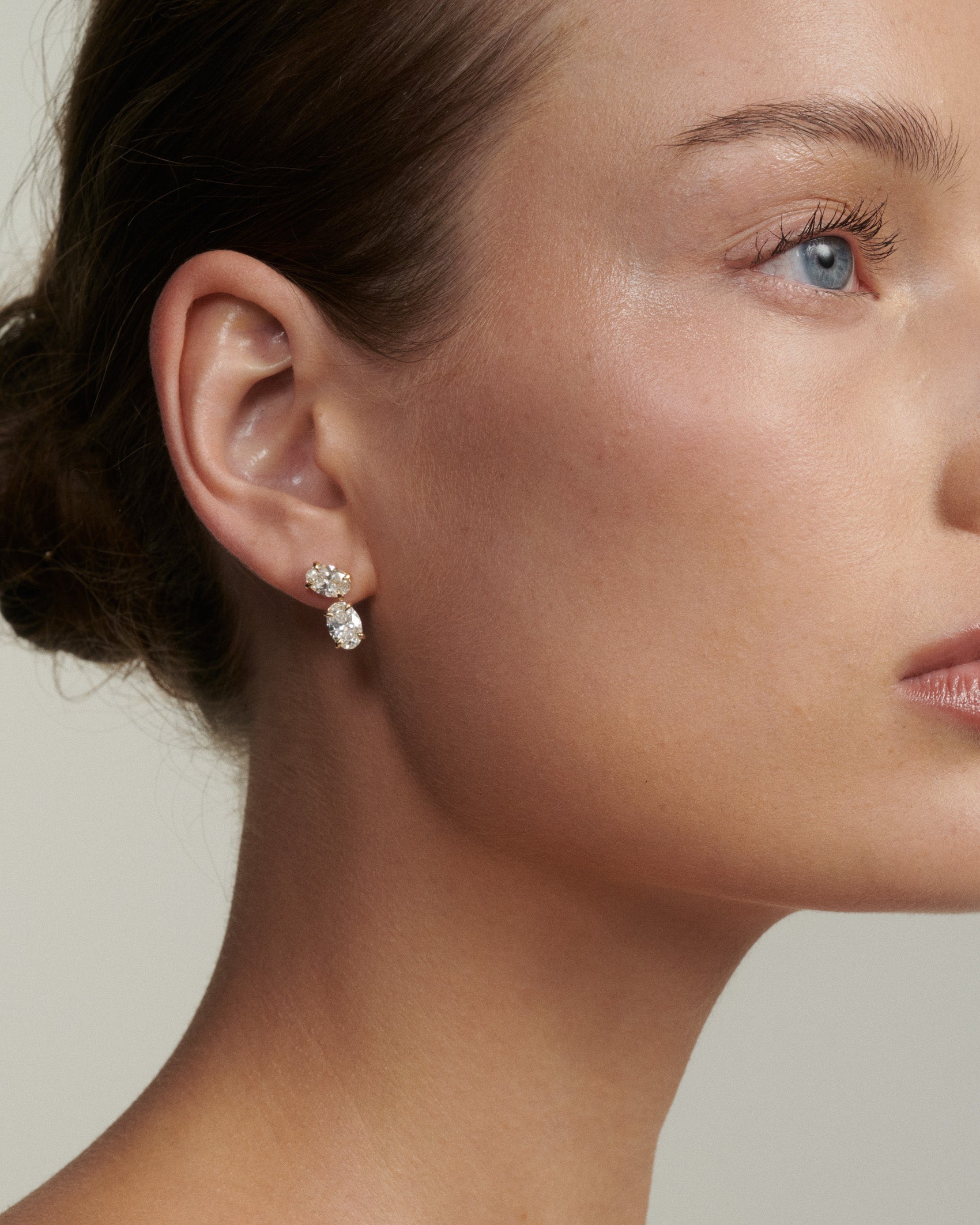 Close-up of a woman wearing a diamond earring with a neutral background