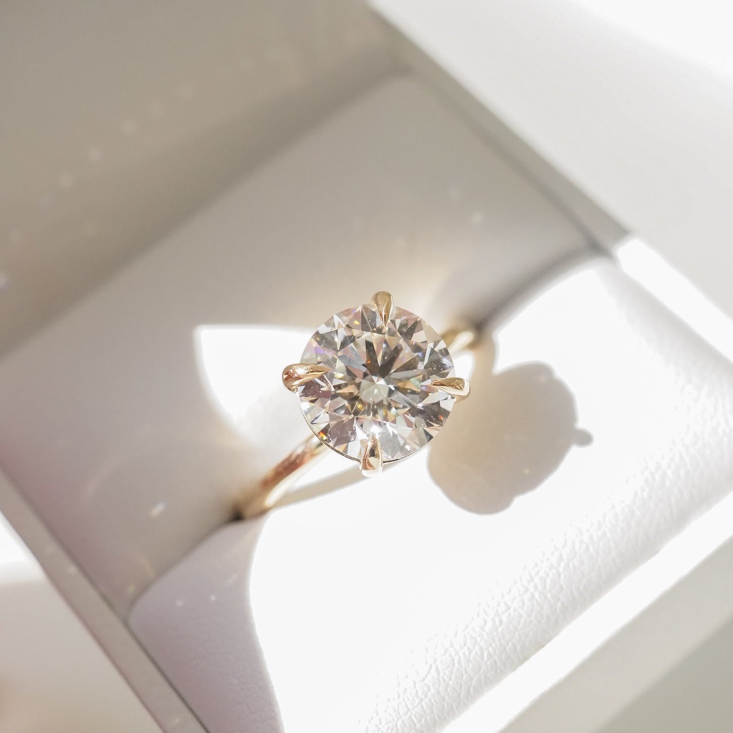 Gold engagement ring with a large, round diamond in a jewellery box, showcasing luxury design and brilliance.