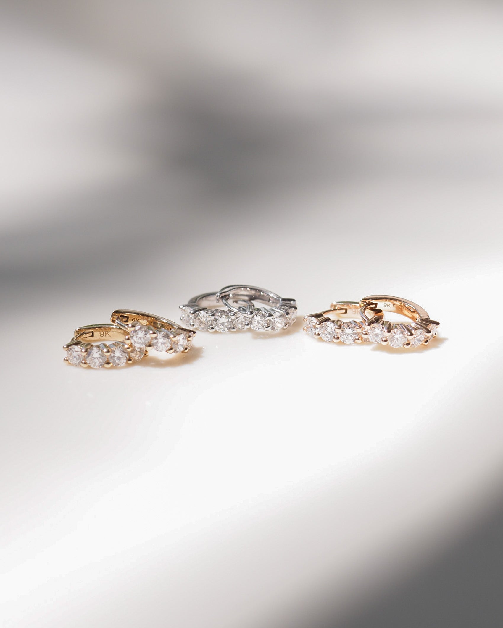[text overlay: Yellow Gold, White Gold & Rose Gold Signature Diamond Huggies] [text colour: #000000]
