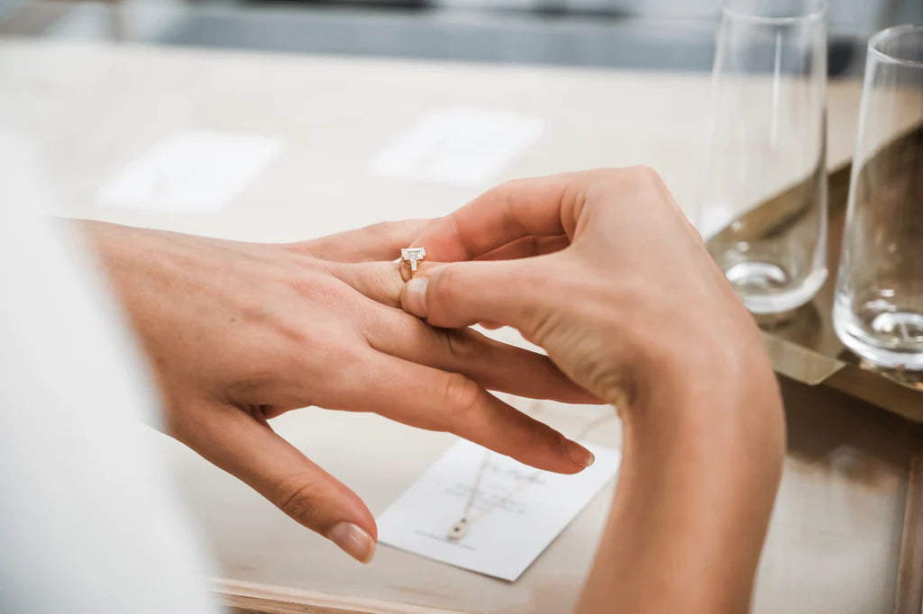 A hand trying on a diamond ring at a jewellery store, with elegant ring design. Luxurious, high-end shopping scene.
