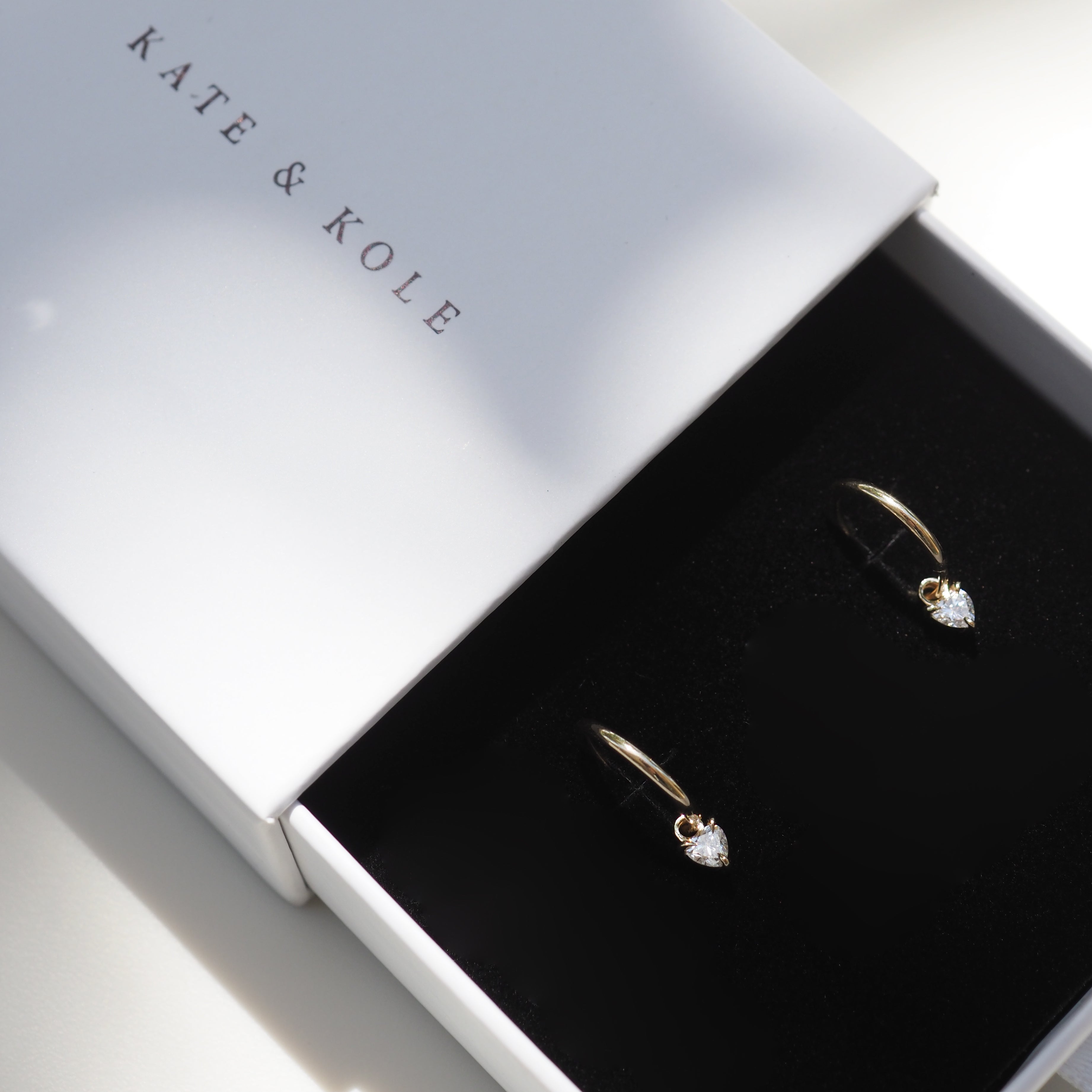 Elegant gold drop earrings with teardrop diamonds in a Kate & Kole branded jewellery box, showcasing luxury and sophistication.