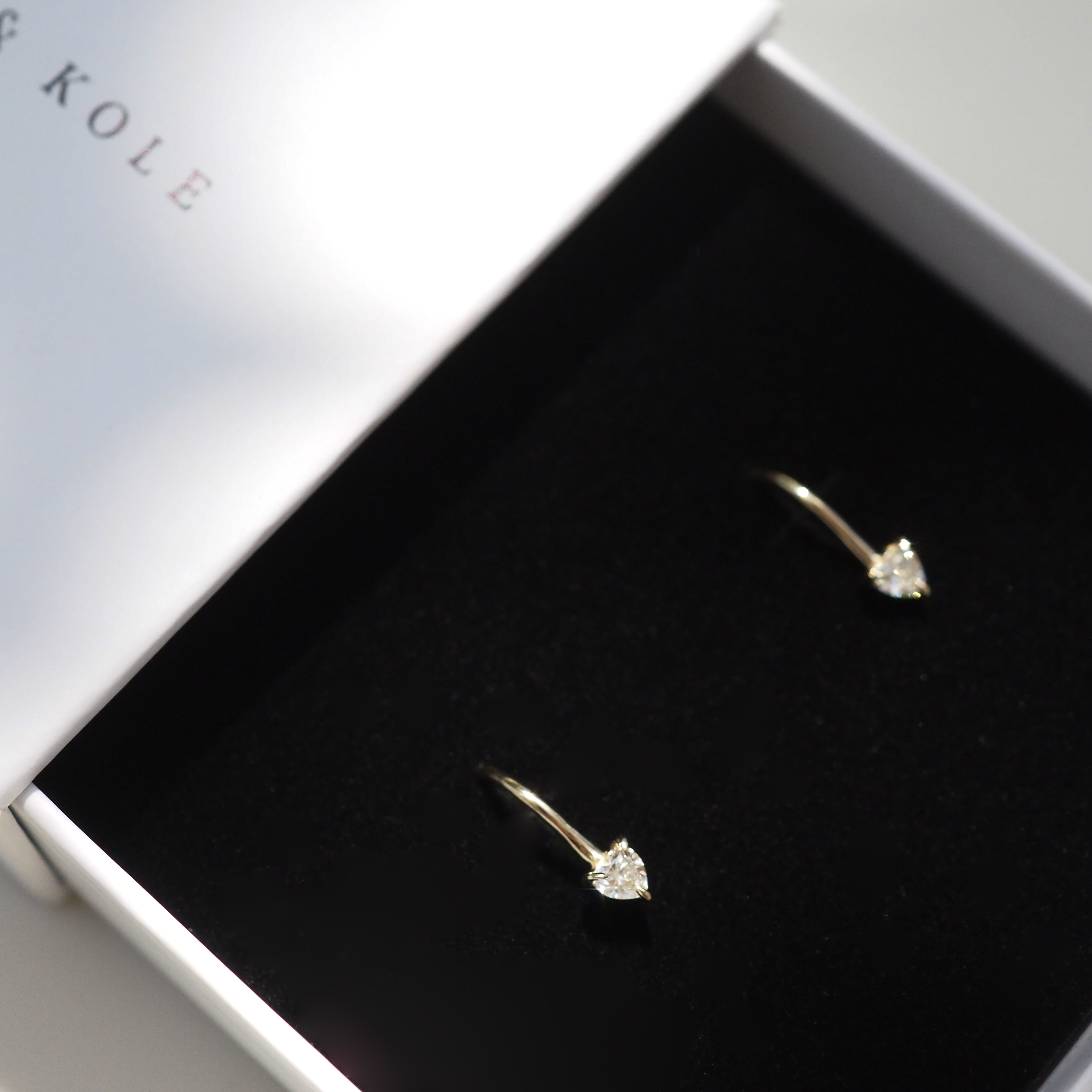Elegant gold earrings with diamond accents in a stylish white jewellery box. Luxurious, minimalist jewellery design.