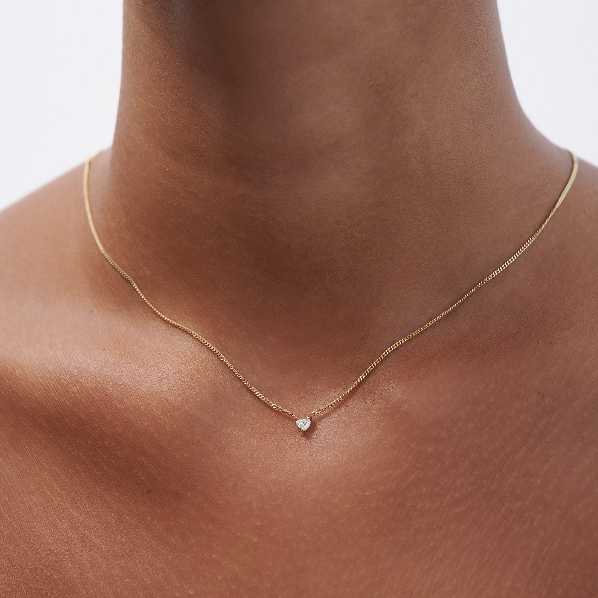 Elegant gold necklace with a small diamond pendant on a collarbone. Luxe jewellery, minimalist style.