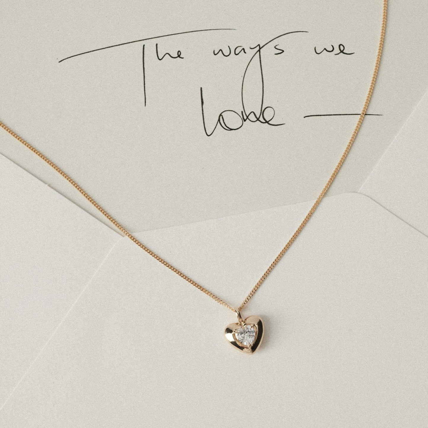 White and cream envelope with yellow gold heart pendant diamond necklace draped 