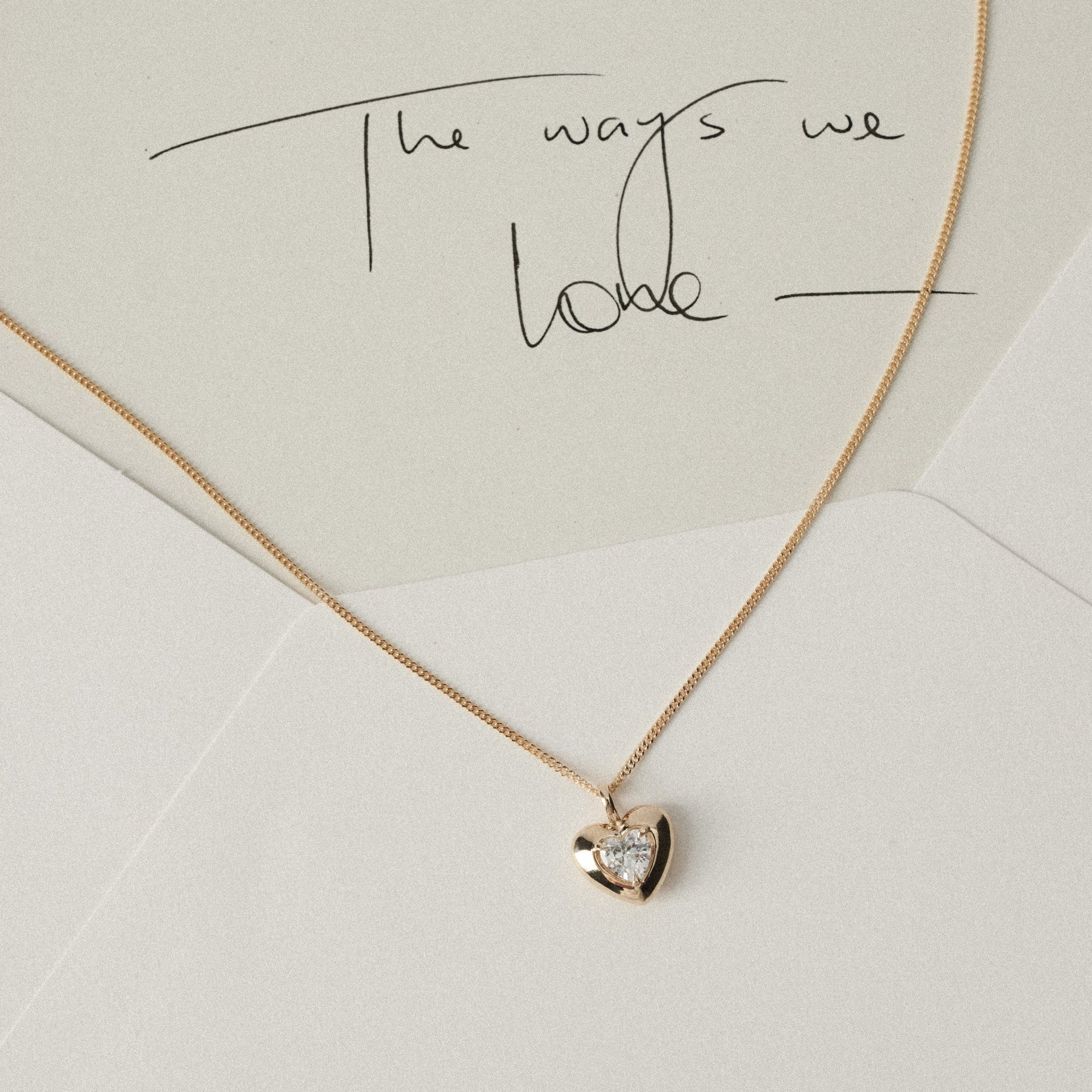 White and cream envelope with yellow gold heart pendant diamond necklace draped 