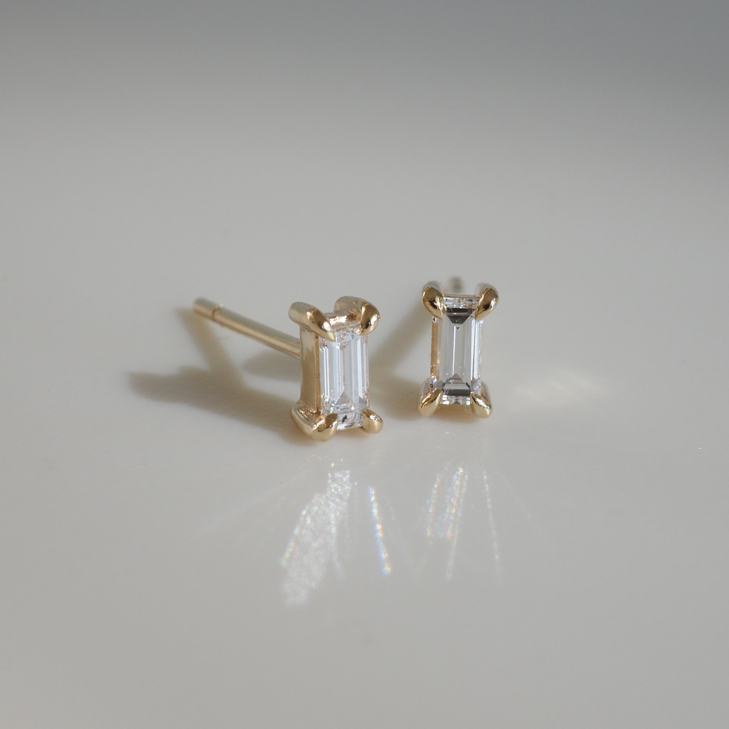 Baguette-cut diamond stud earrings set in gold, radiant on a light surface. Perfect for elegant, timeless luxury jewellery lovers.
