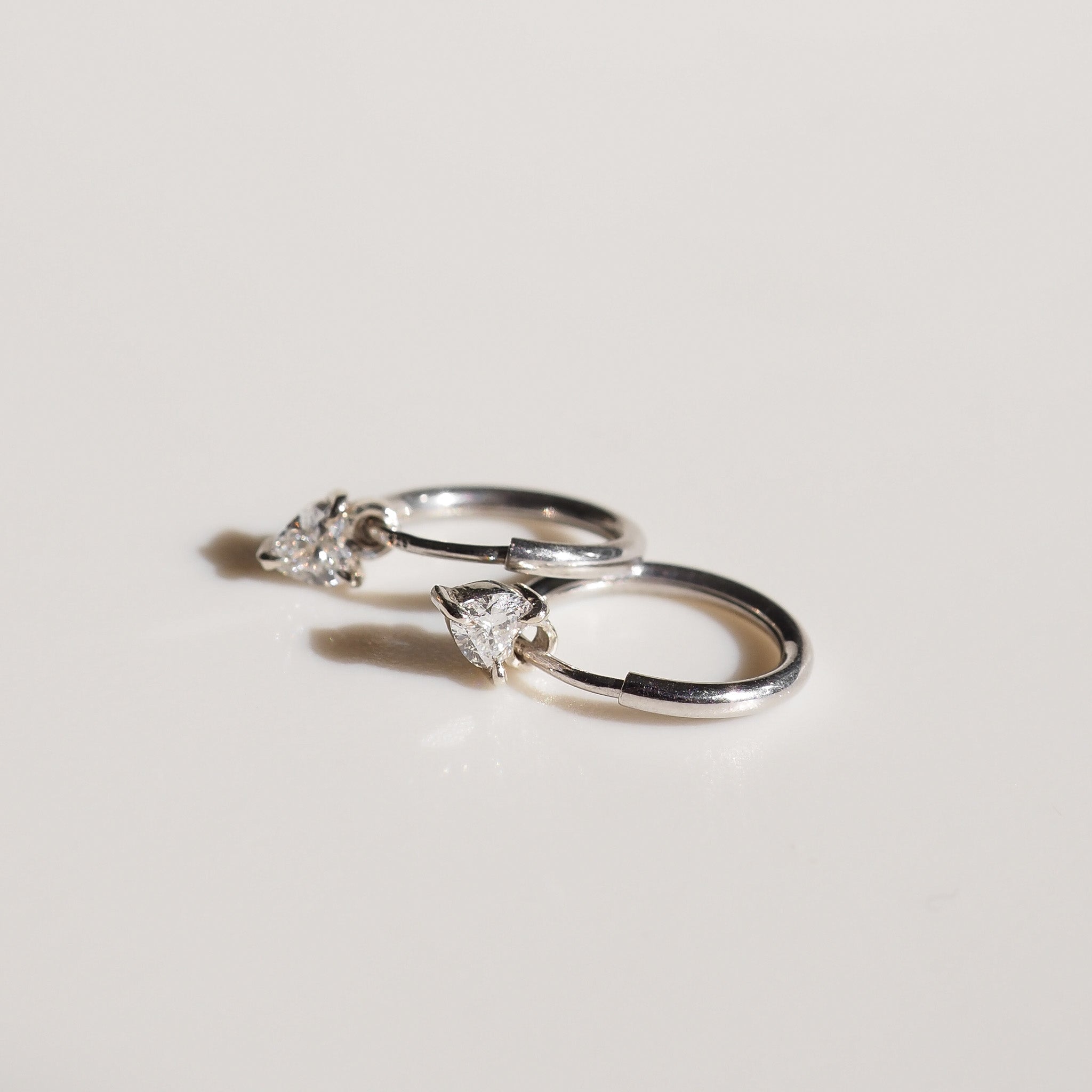 Pair of silver hoop earrings with clear gemstones on a light gray background