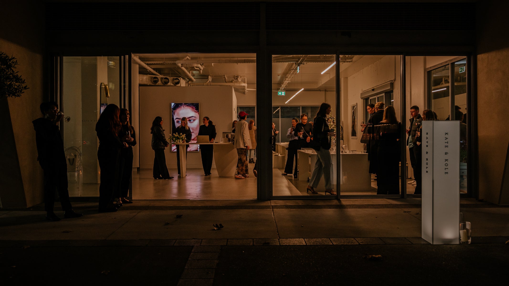 Luxury jewellery event with guests mingling inside a modern, well-lit showroom. A large jewellery display and artwork are visible inside.