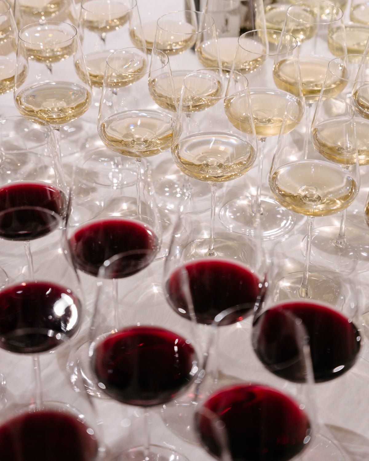 Rows of red and white wine glasses arranged on a table, reflecting luxury and elegance, perfect for a high-end jewellery event.