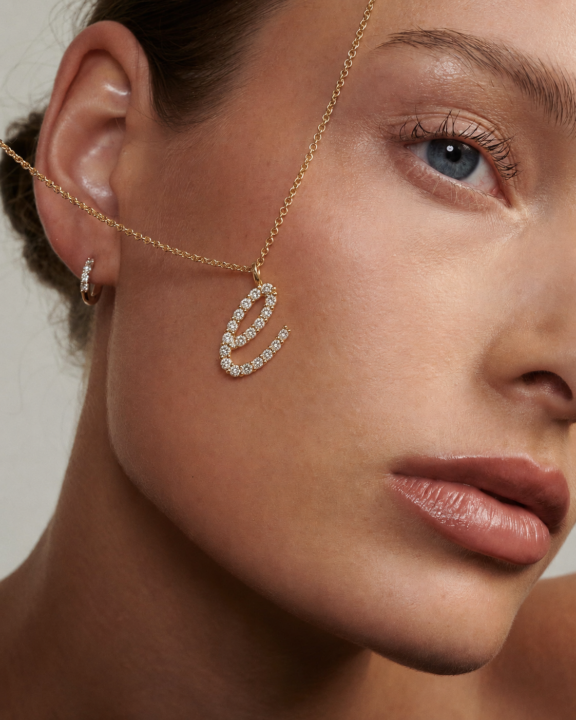 Close-up of a woman's face wearing a gold necklace with a diamond pendant.