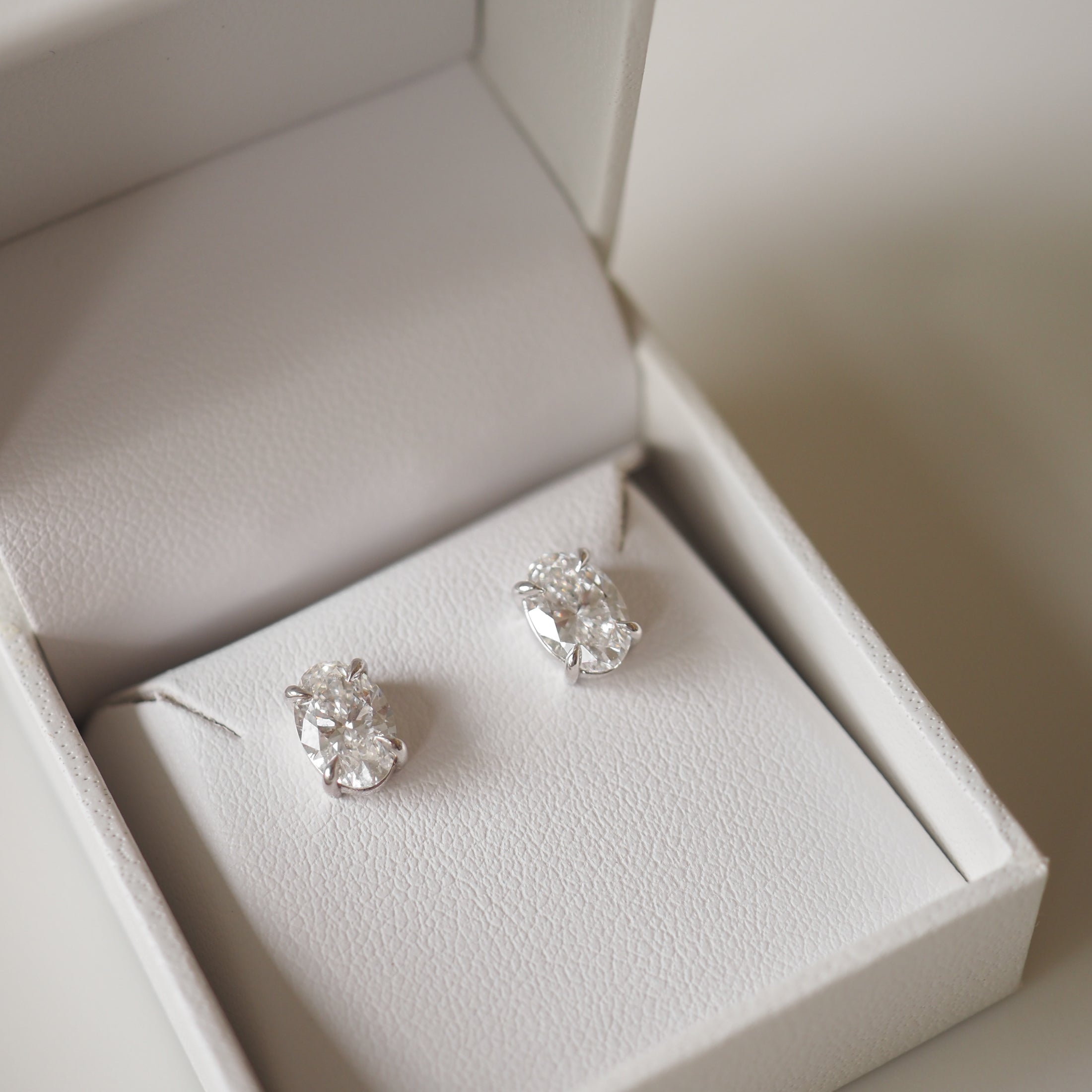 Elegant diamond stud earrings in a white jewellery box, showcasing luxury fine jewellery. Perfect for high-end fashion or special occasions.