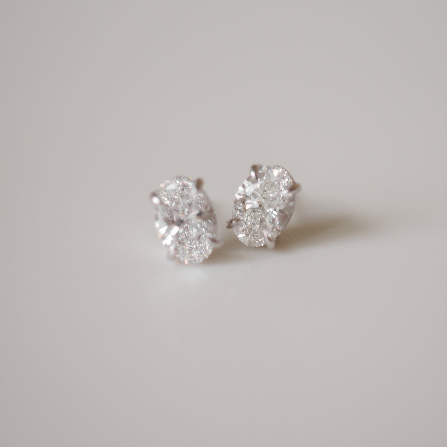 Elegant diamond stud earrings on a soft grey background, showcasing luxury jewellery craftsmanship.