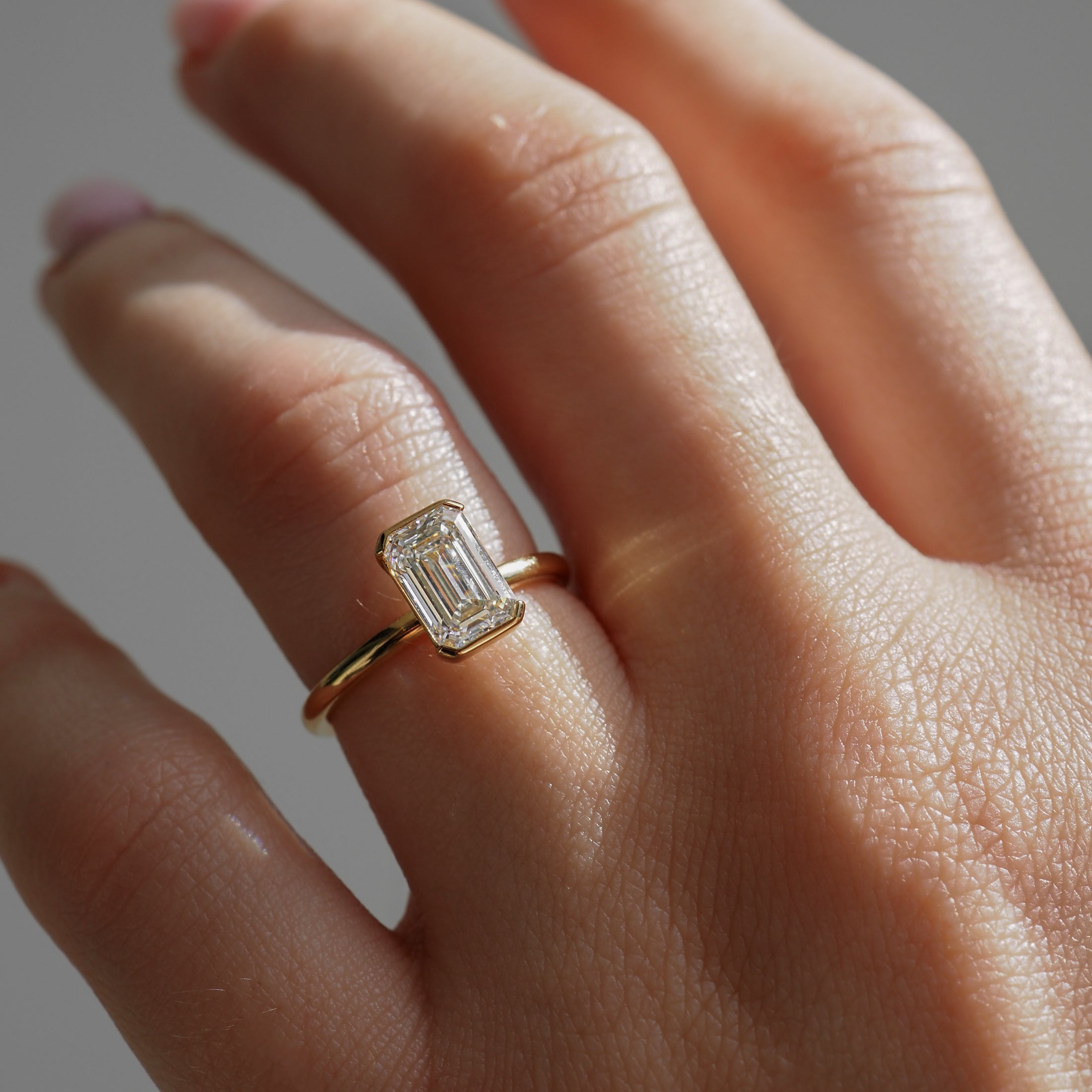 Close-up of a hand wearing a gold ring with a large emerald-cut diamond, showcasing luxury jewellery, elegance, and craftsmanship.