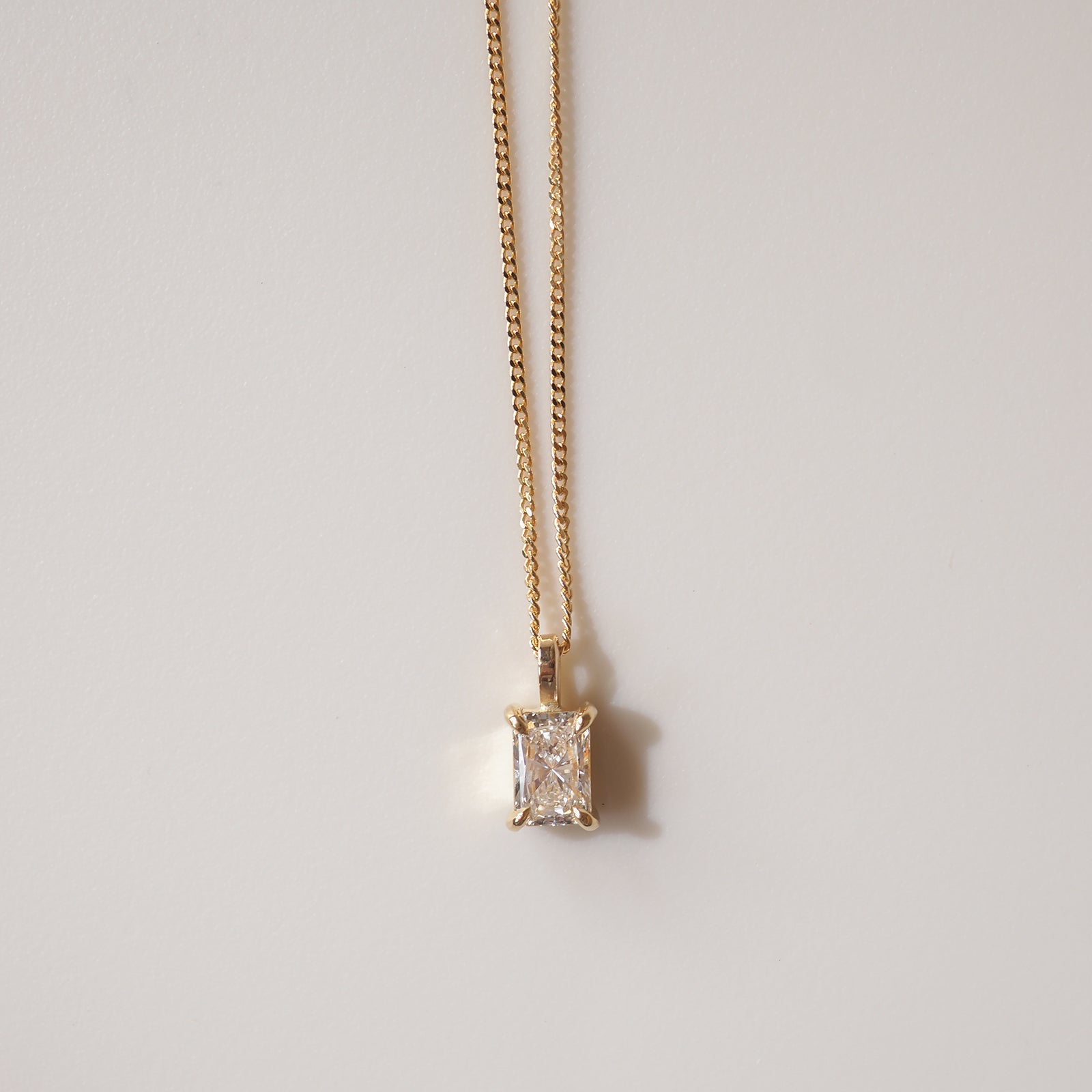 Gold chain necklace with rectangular diamond pendant, showcasing luxury jewellery elegance against a plain background.