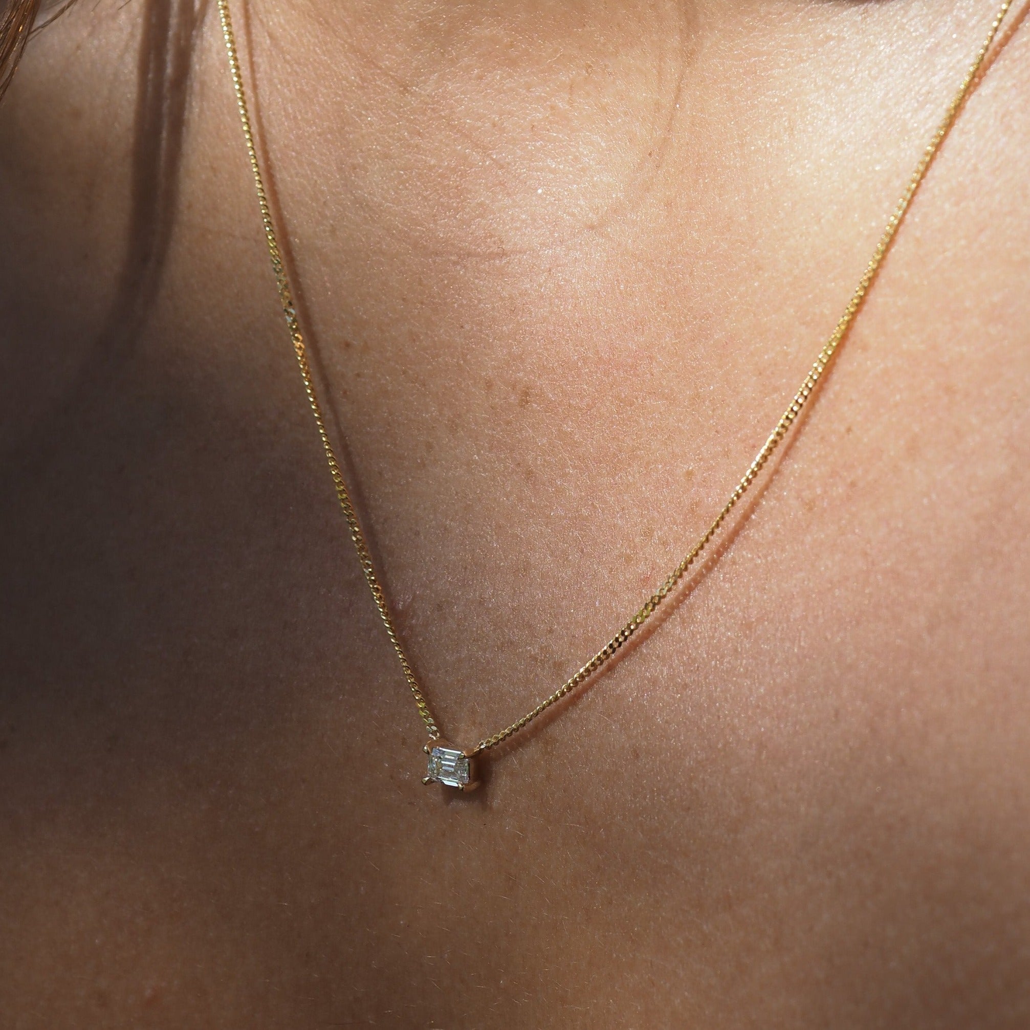 Elegant Emerald diamond necklace featured on yellow gold chain. 