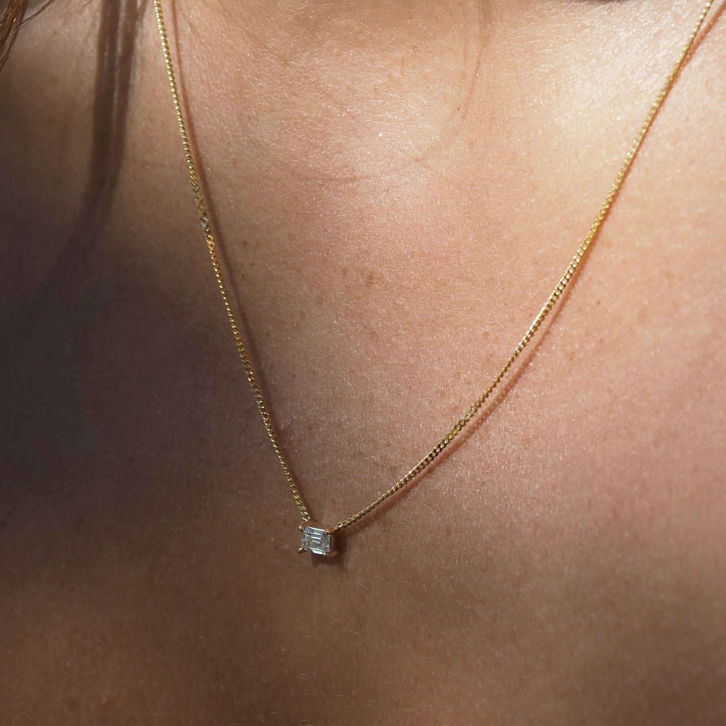 Elegant Emerald diamond necklace featured on yellow gold chain.