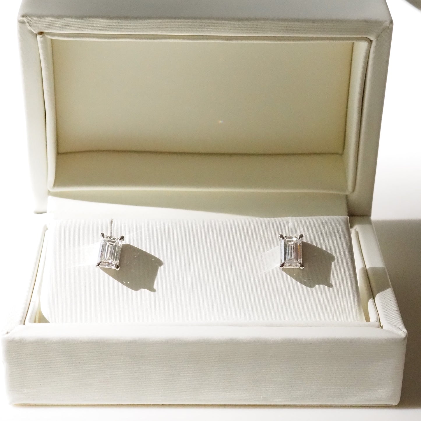 Silver earrings in an open jewelry box on a white background