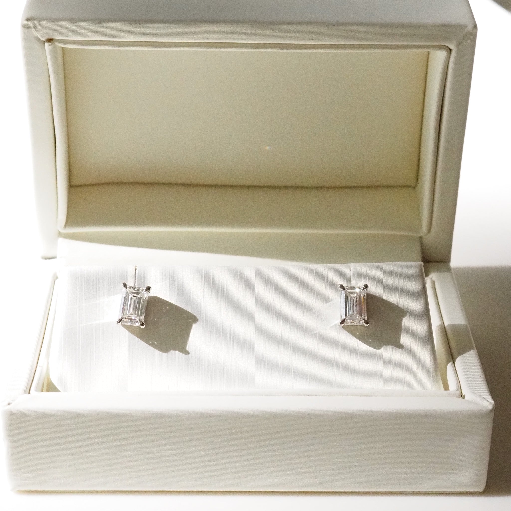 Silver earrings in an open jewelry box on a white background