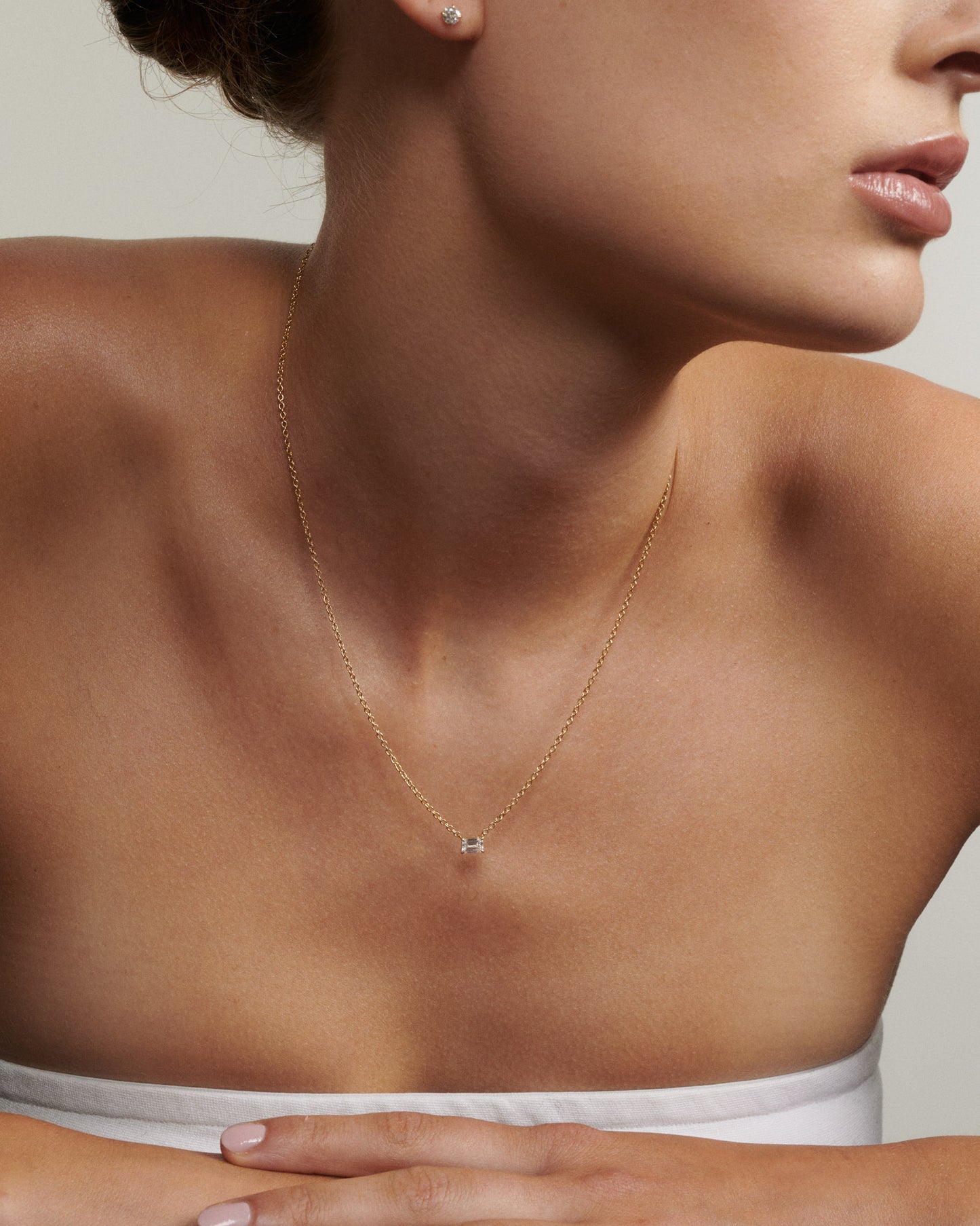 Close-up of a woman wearing a delicate necklace with a small pendant.