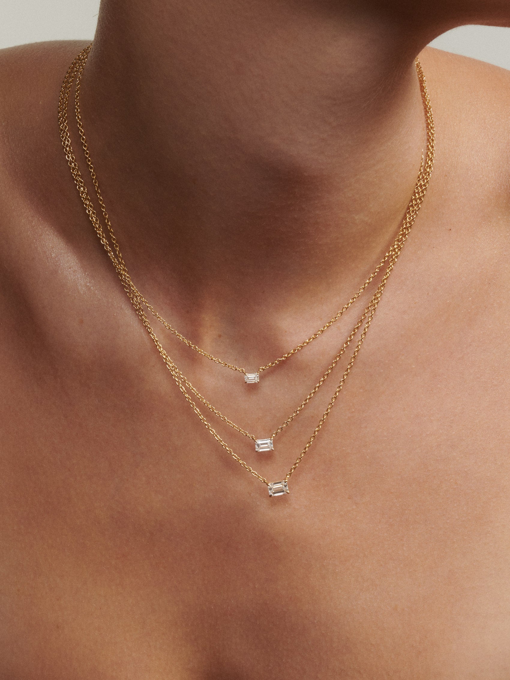 Gold necklaces with gemstones on a person's neck [text overlay: 0.25ct, 0.5ct, 0.75ct (top to bottom)]