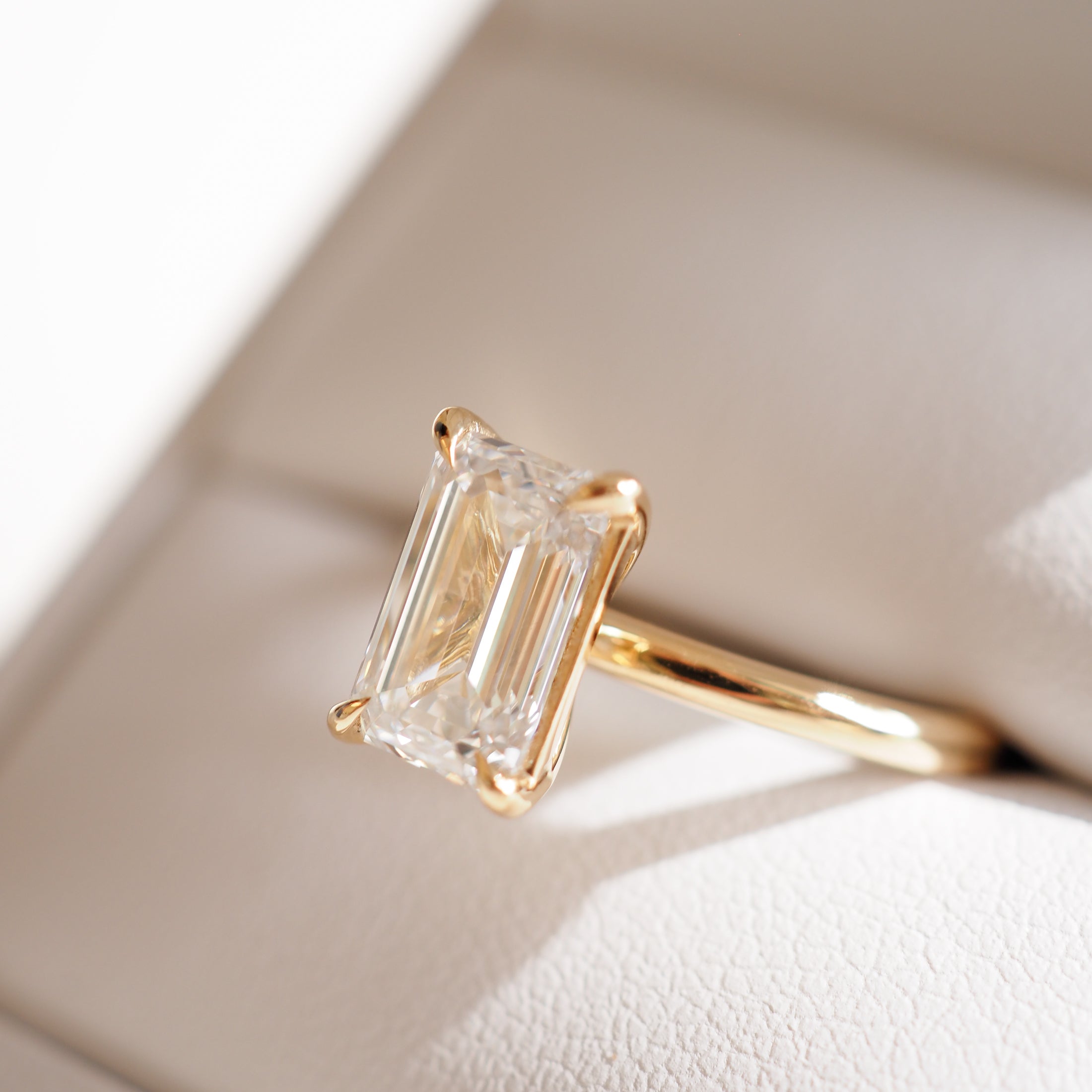 Emerald-cut diamond ring with a gold band in a luxury jewellery box, highlighting its brilliance and elegance under soft lighting.