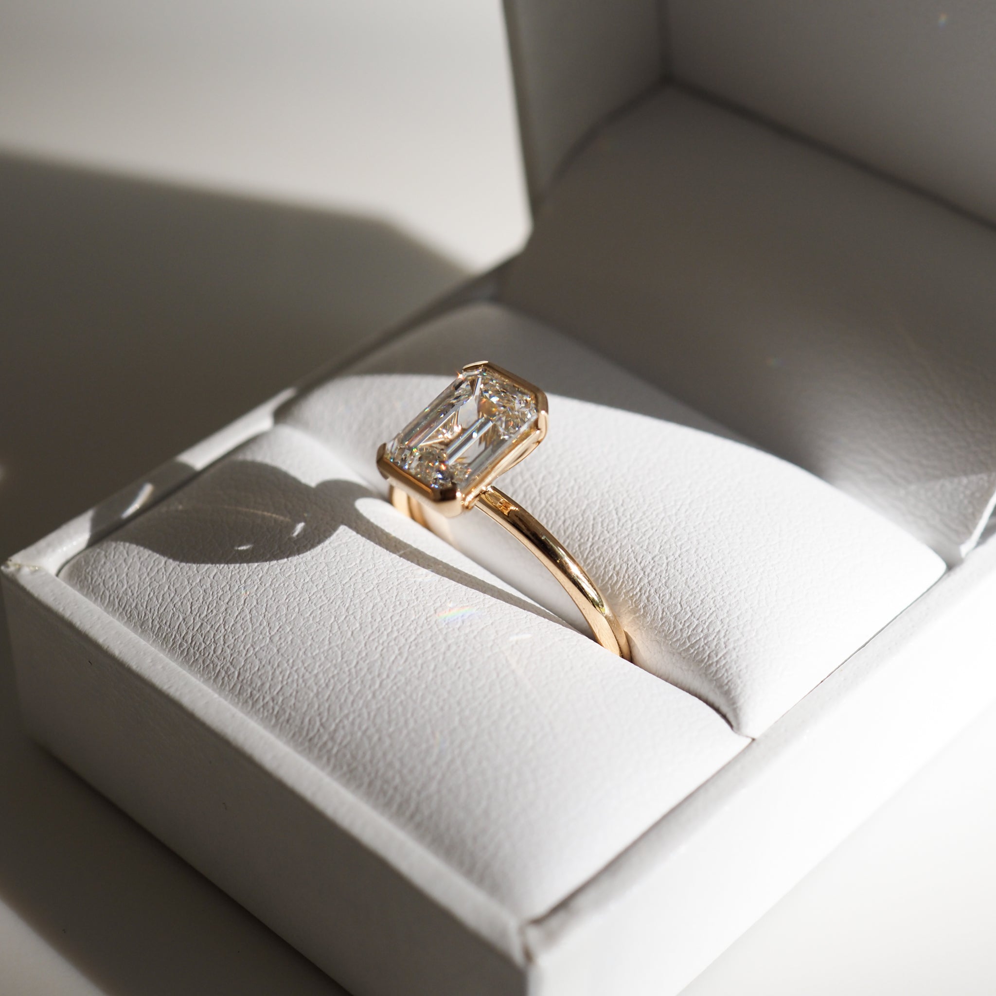 Emerald-cut diamond ring with gold band in an open white jewellery box, showcasing luxury and elegance in fine Australian jewellery.