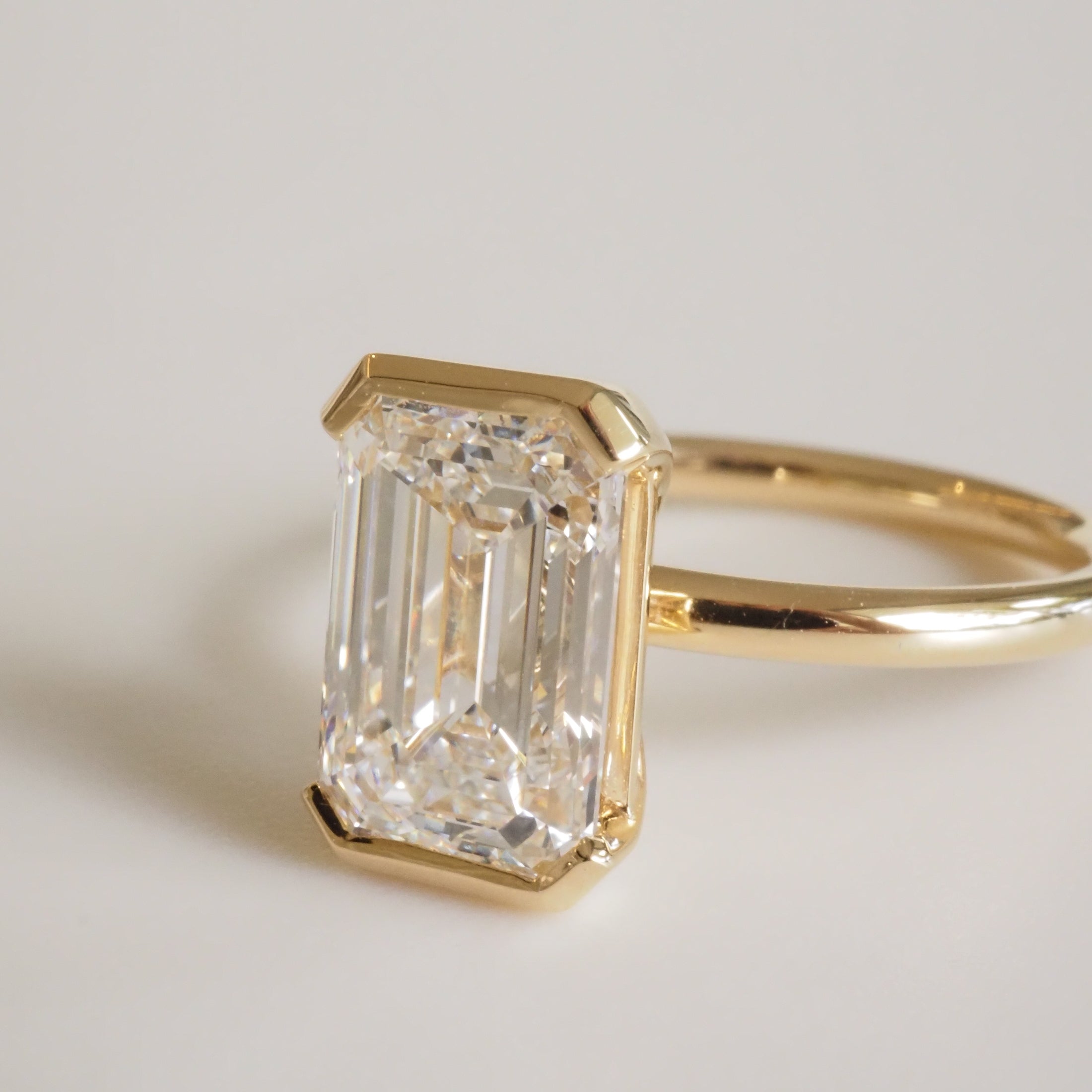 Emerald-cut diamond ring in yellow gold setting, showcasing luxurious elegance and brilliance.