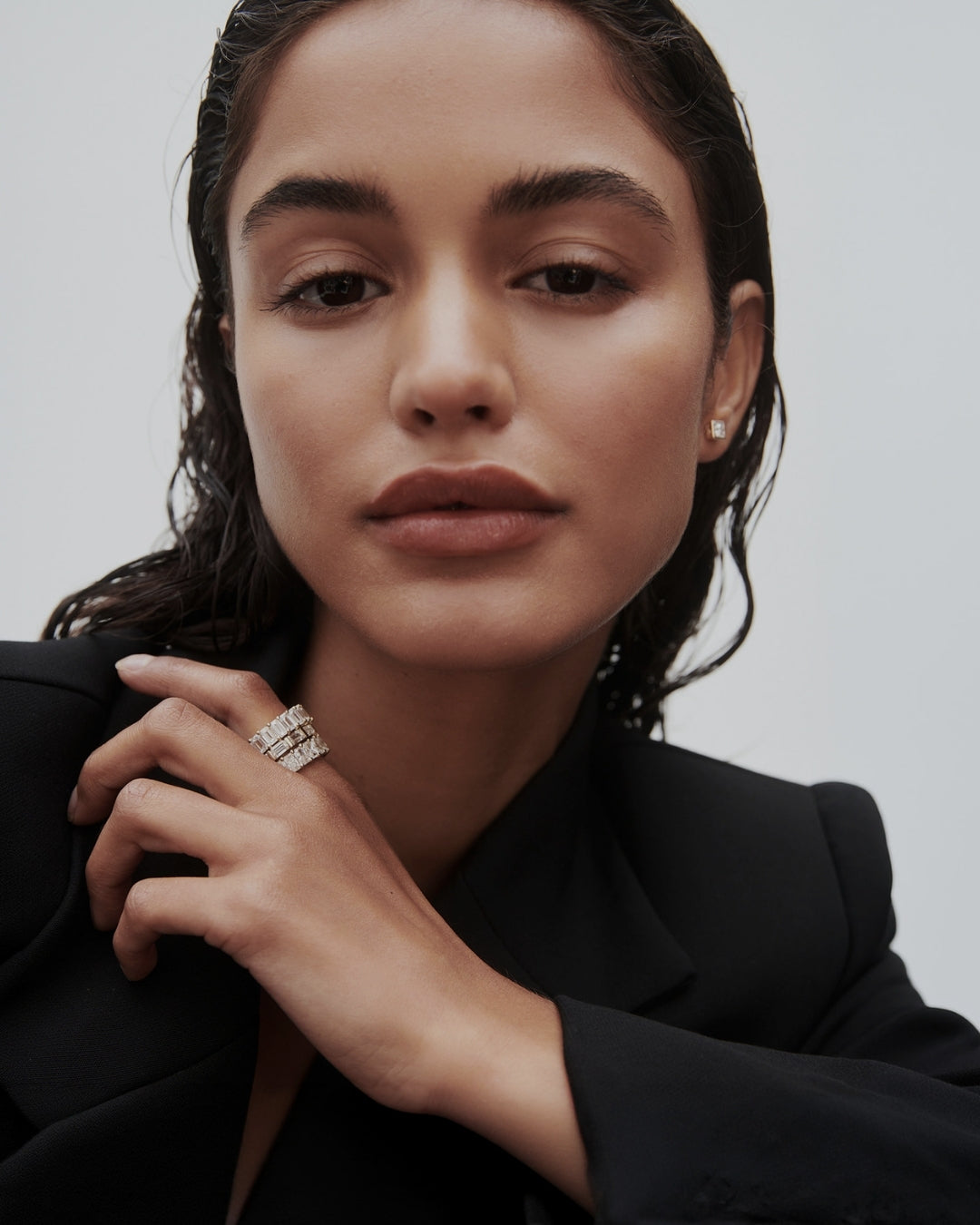 Model wearing a stack of yellow gold diamond bands featuring mixed diamond cuts with a grey backdrop