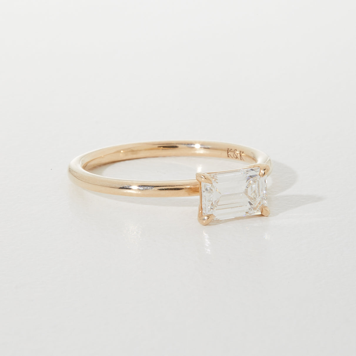Gold band ring with a rectangular emerald-cut diamond solitaire. Simple, elegant design, ideal for luxury and high-end jewellery lovers.