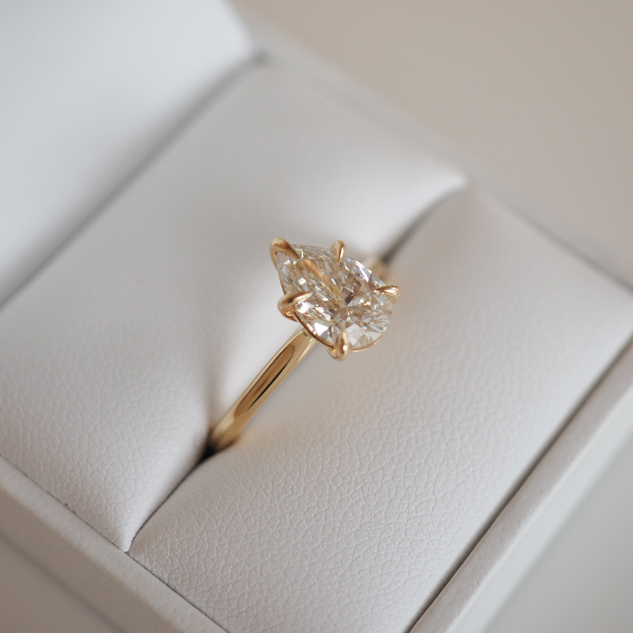 Gold ring with a large, clear diamond set in a classy prong setting, displayed in a white jewellery box. Luxurious and elegant design.