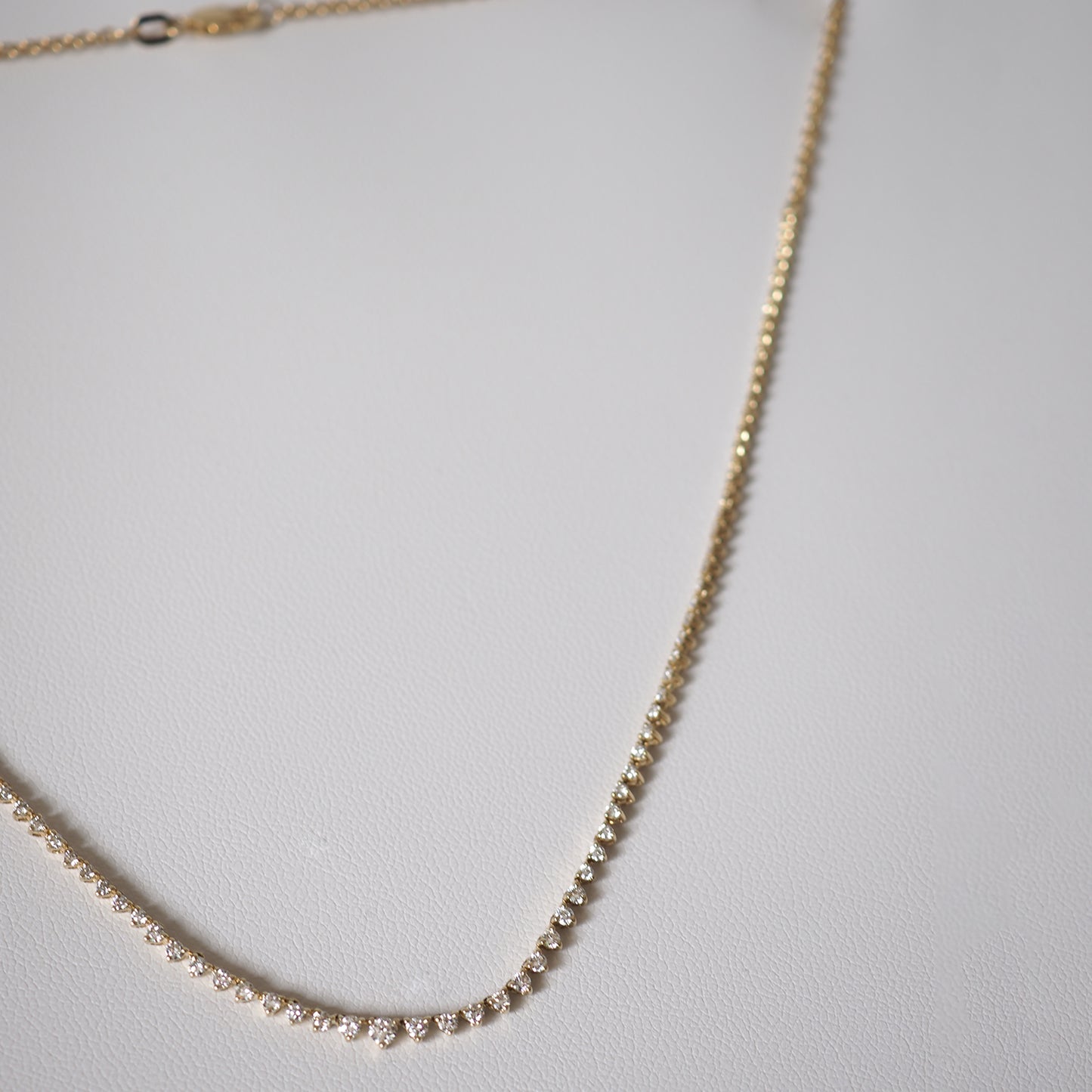Elegant gold necklace adorned with sparkling diamonds, displayed on a white surface. Perfect luxury jewellery piece.