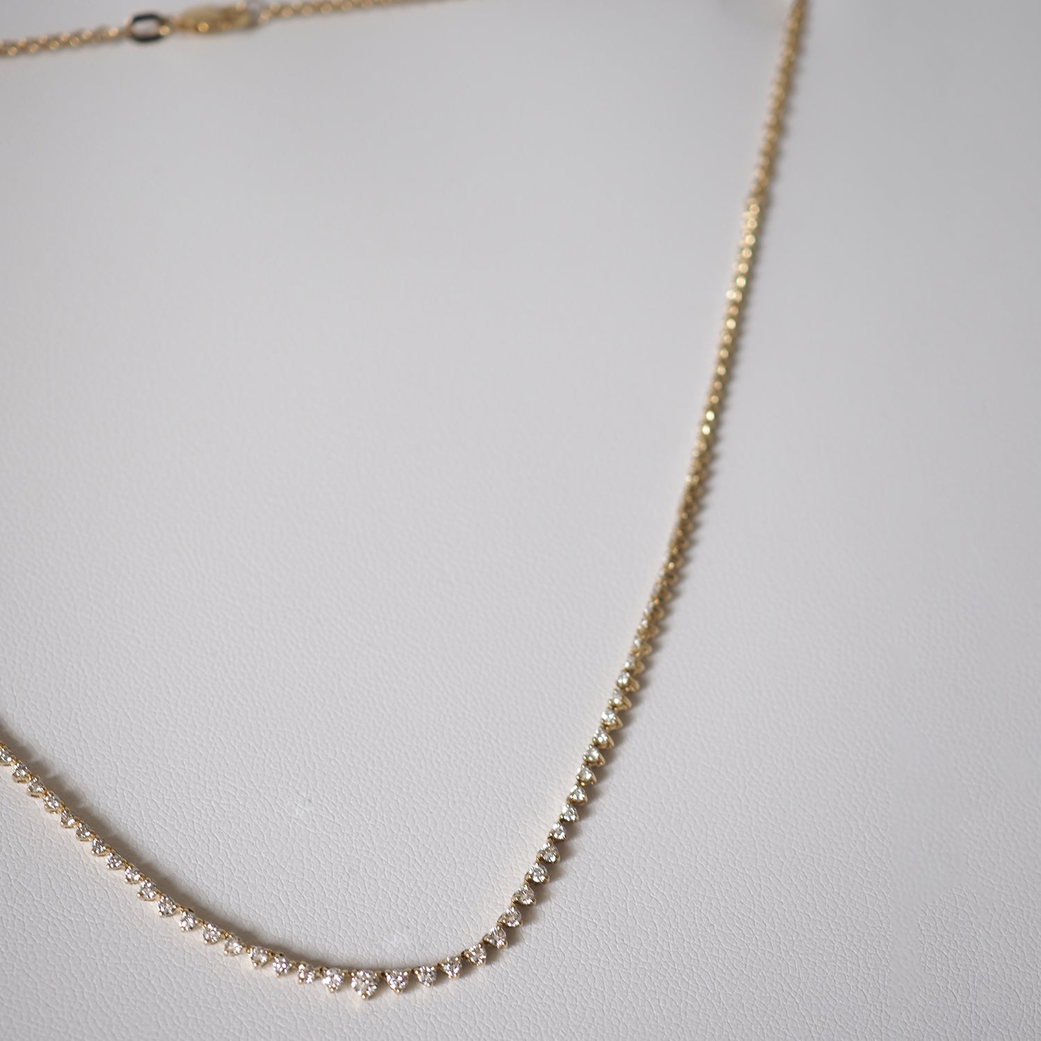 Elegant gold necklace adorned with sparkling diamonds, displayed on a white surface. Perfect luxury jewellery piece.